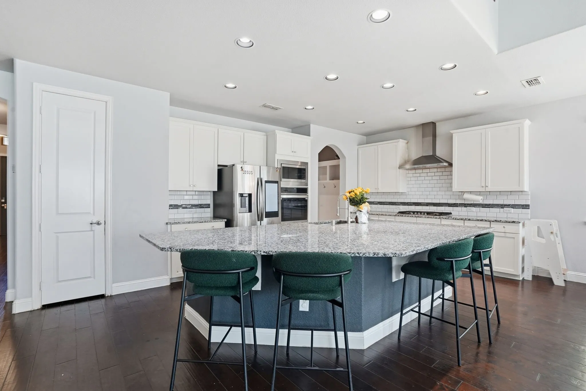 Kitchen featuring backsplash, recessed lighting, a breakfast bar area, a center island with sink, and light stone countertops