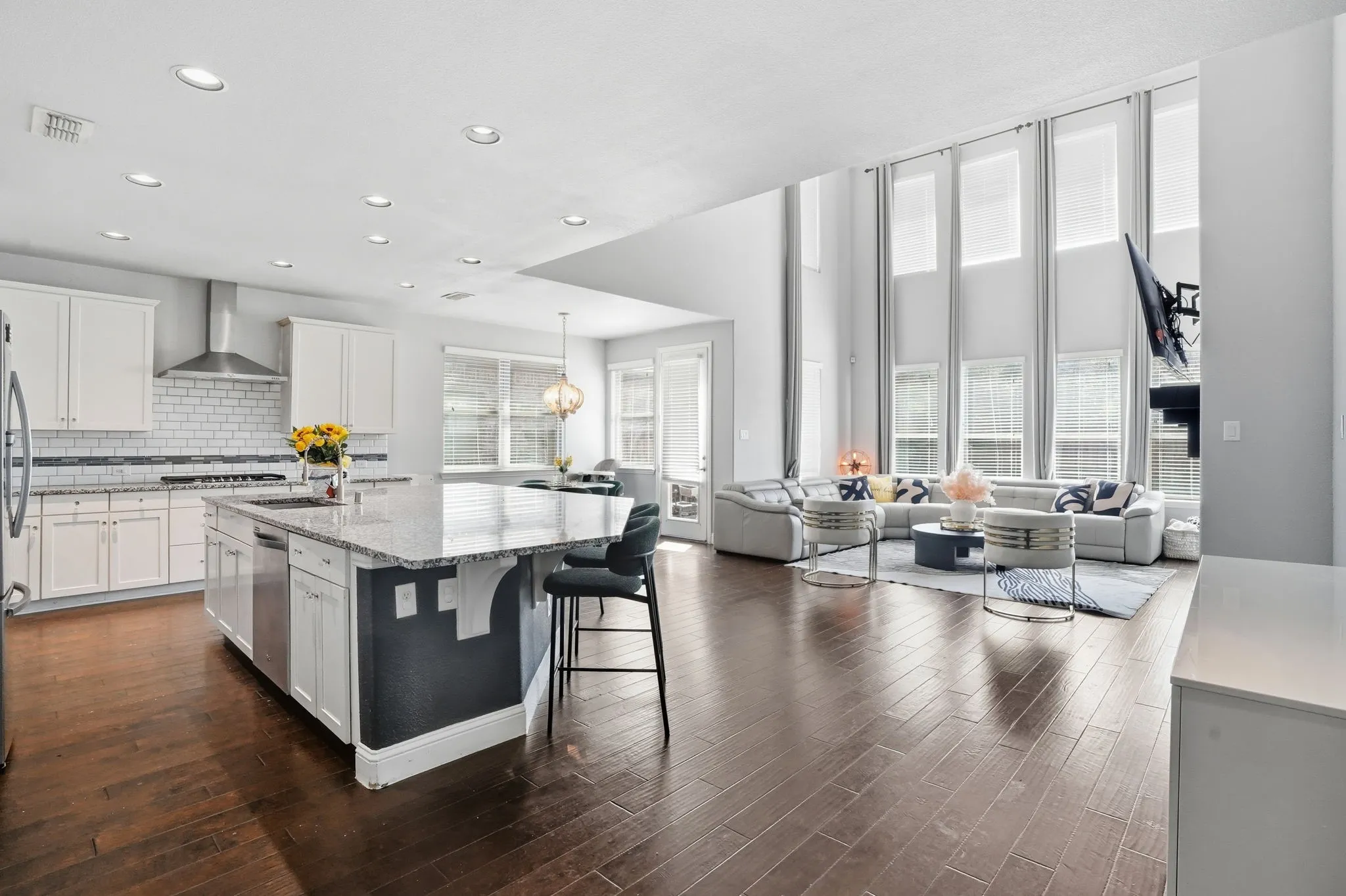 Kitchen featuring healthy amount of natural light, white cabinets, light stone countertops, tasteful backsplash, and recessed lighting