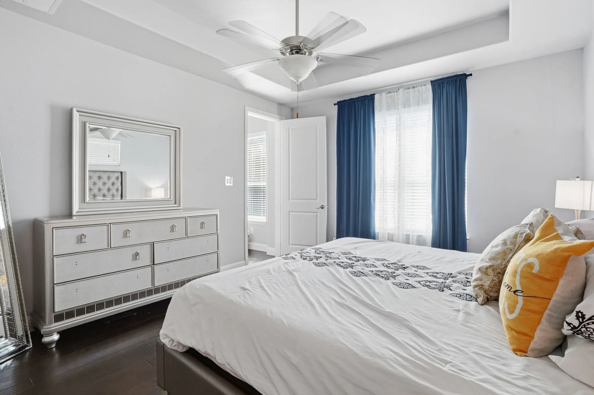 Bedroom with a tray ceiling, dark wood-type flooring, and ceiling fan