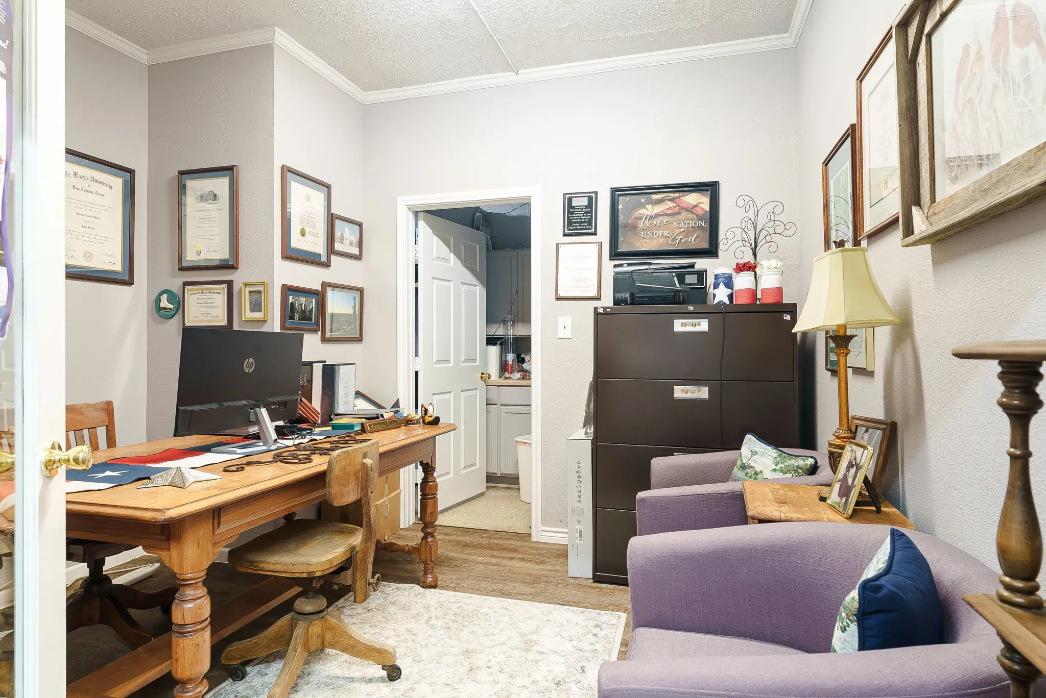 Office area featuring ornamental molding, light wood finished floors, and a textured ceiling