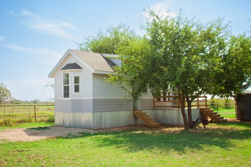 View of side of property featuring a shingled roof and stairs