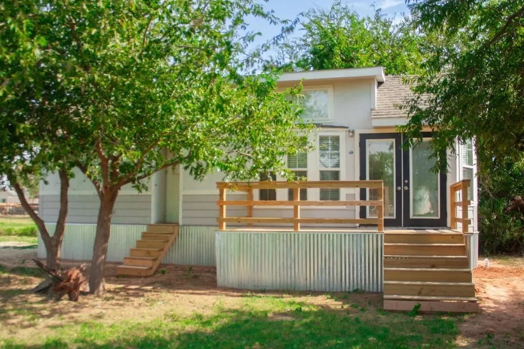Back of house with a deck, roof with shingles, stairs, and stucco siding