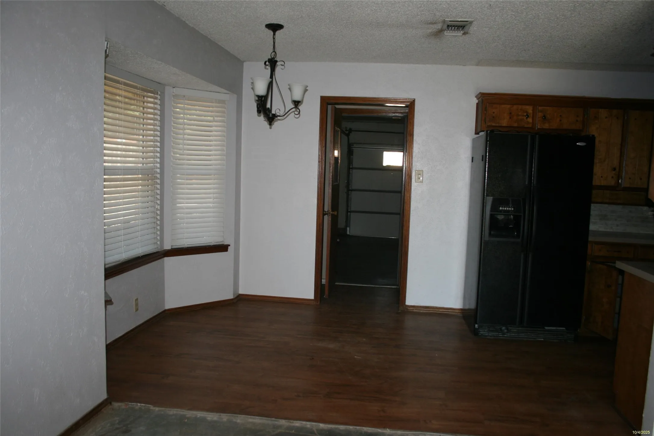Unfurnished dining area with dark wood-style floors, a textured ceiling, and a chandelier