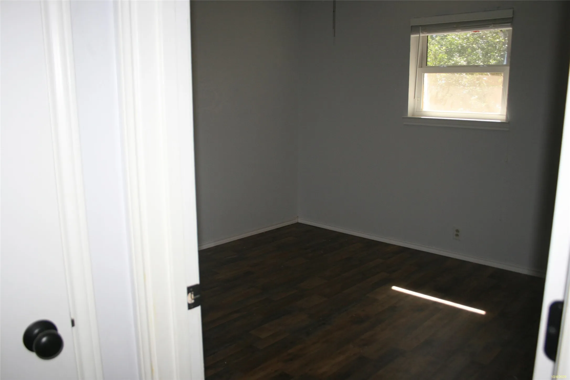 Empty room featuring dark wood-style floors and baseboards
