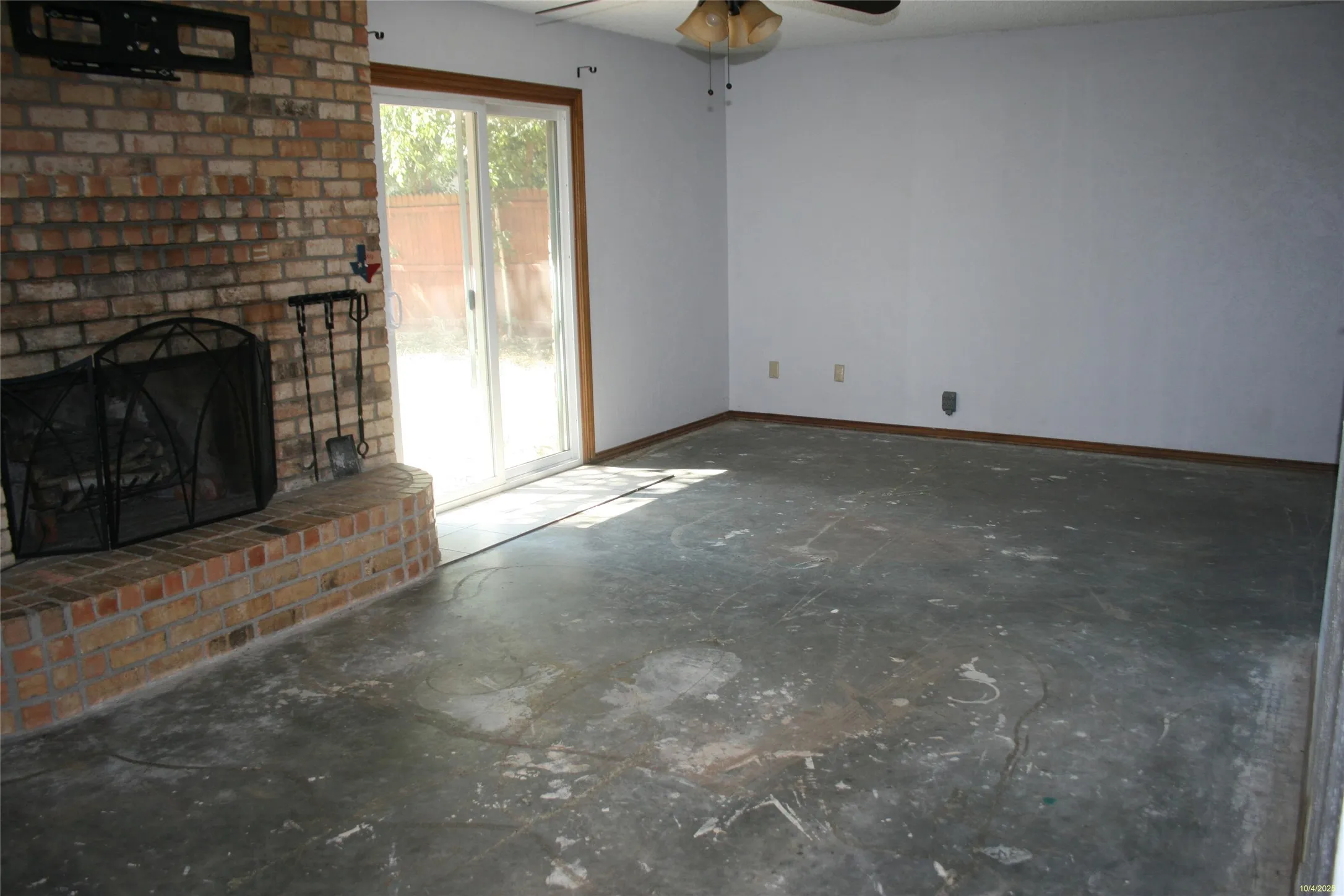 Unfurnished living room with a fireplace, a ceiling fan, and concrete floors