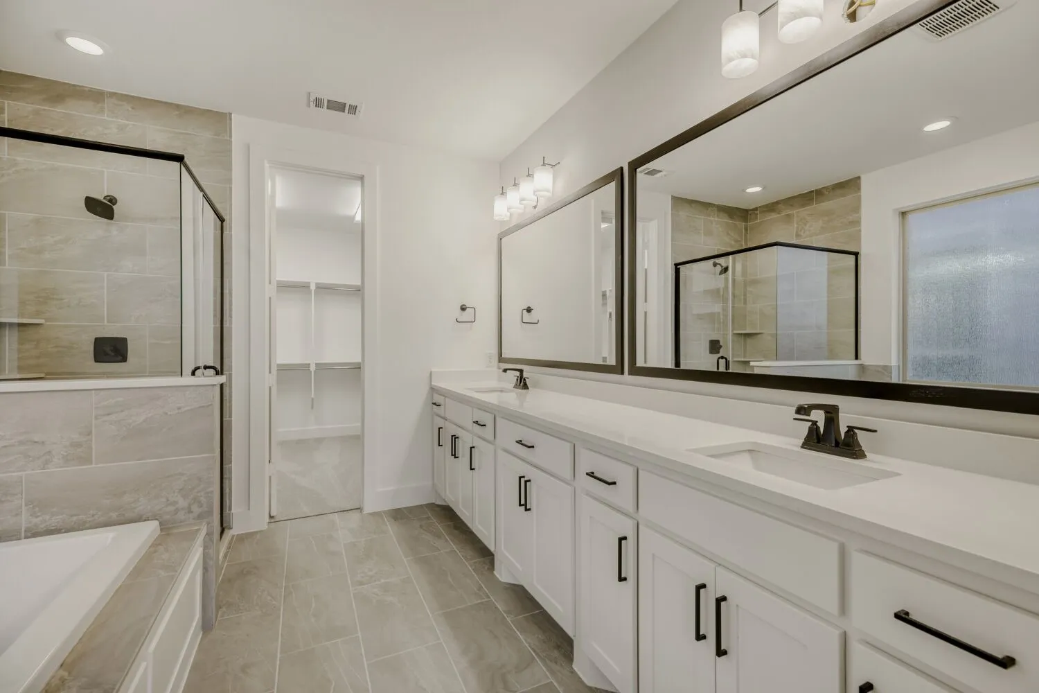 Full bath featuring double vanity, a bath, a shower stall, a spacious closet, and recessed lighting