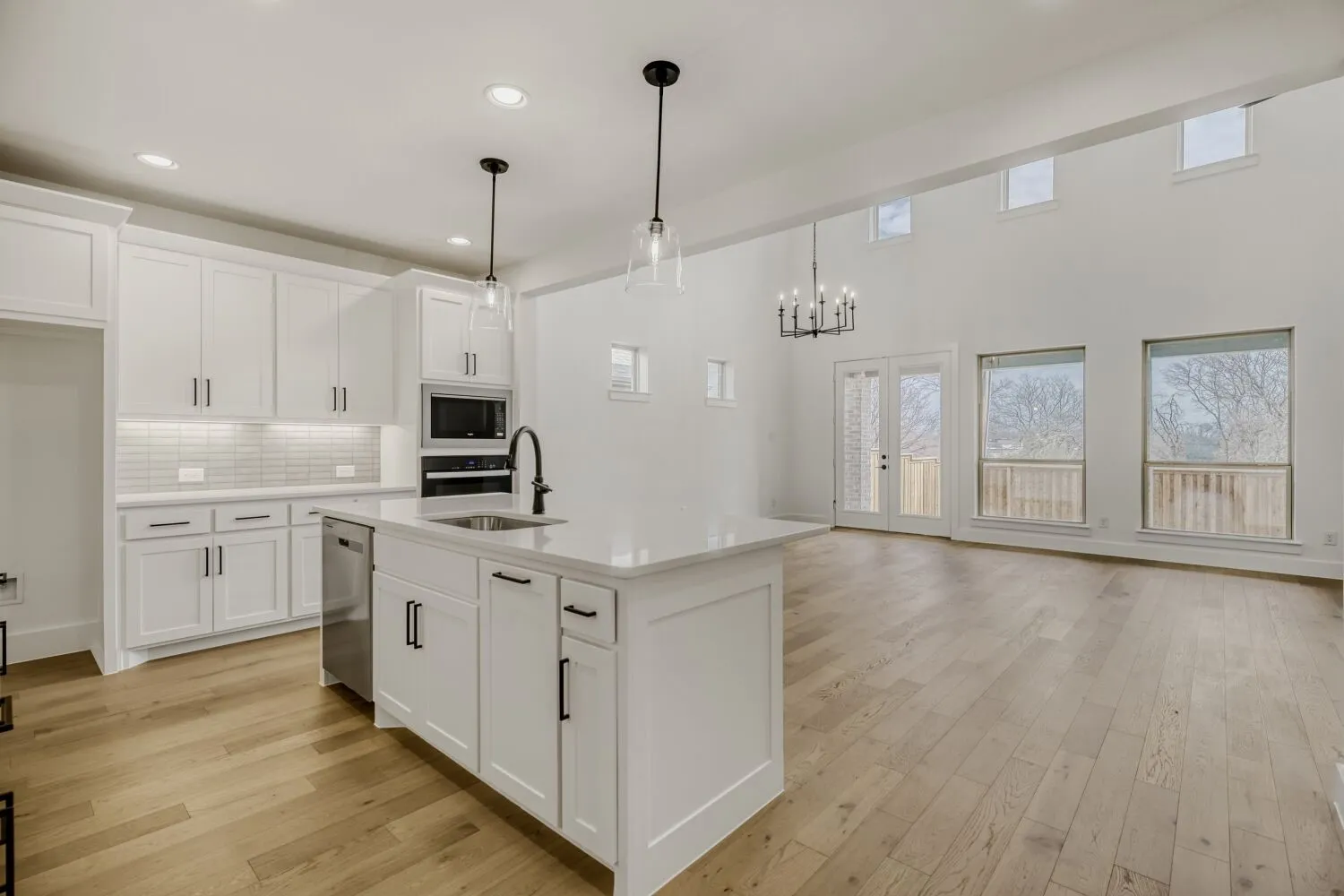 Kitchen featuring light wood-style floors, white cabinetry, a kitchen island with sink, decorative backsplash, and wall oven