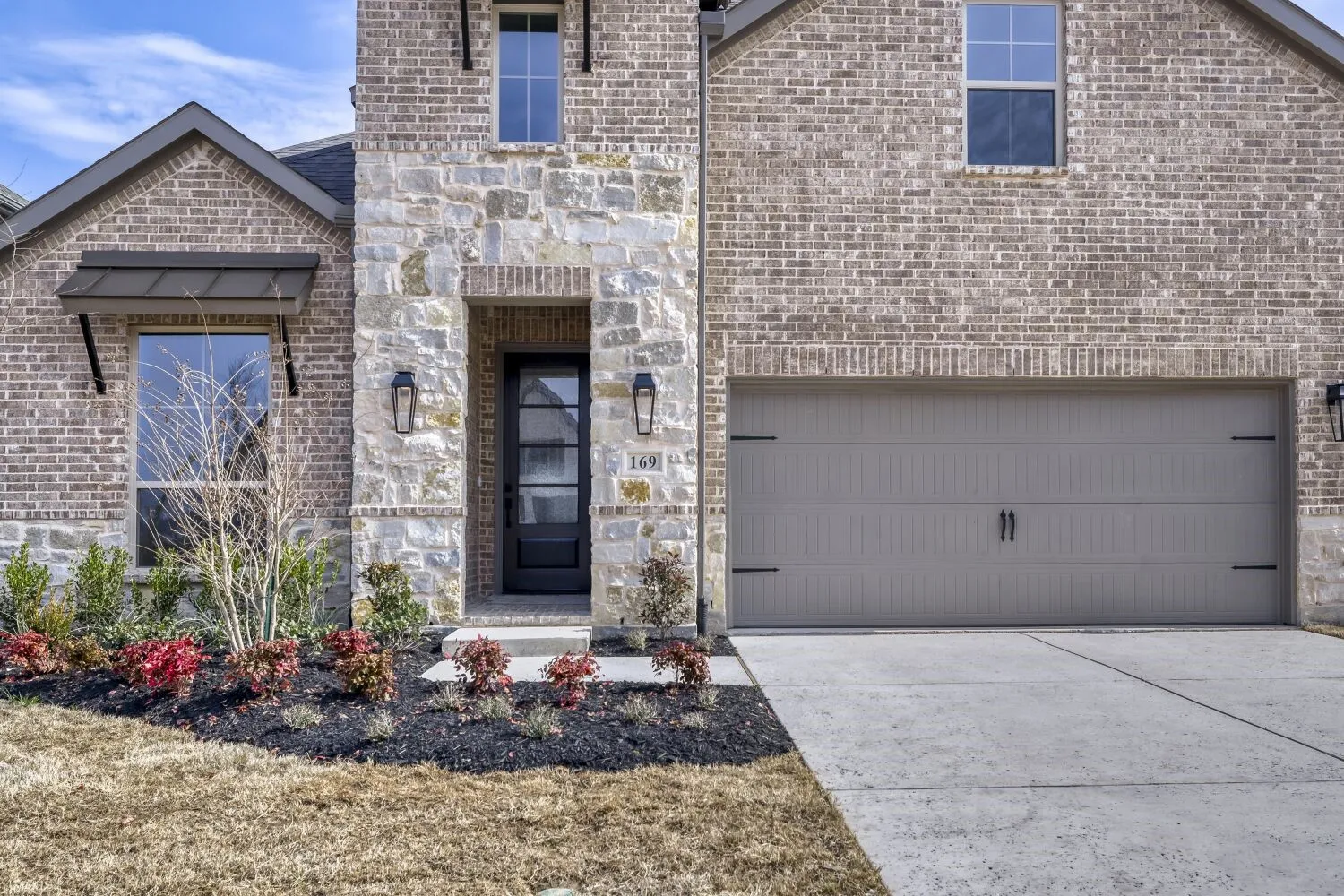 View of front of house featuring concrete driveway, brick siding, an attached garage, and stone siding