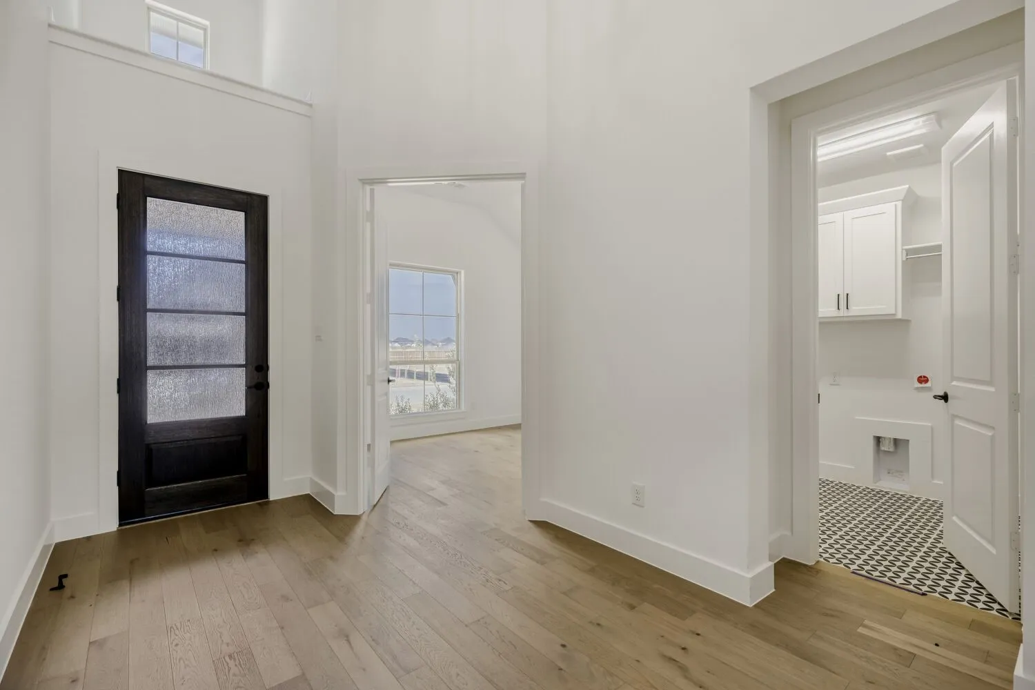 Entrance foyer with light wood-type flooring and a high ceiling