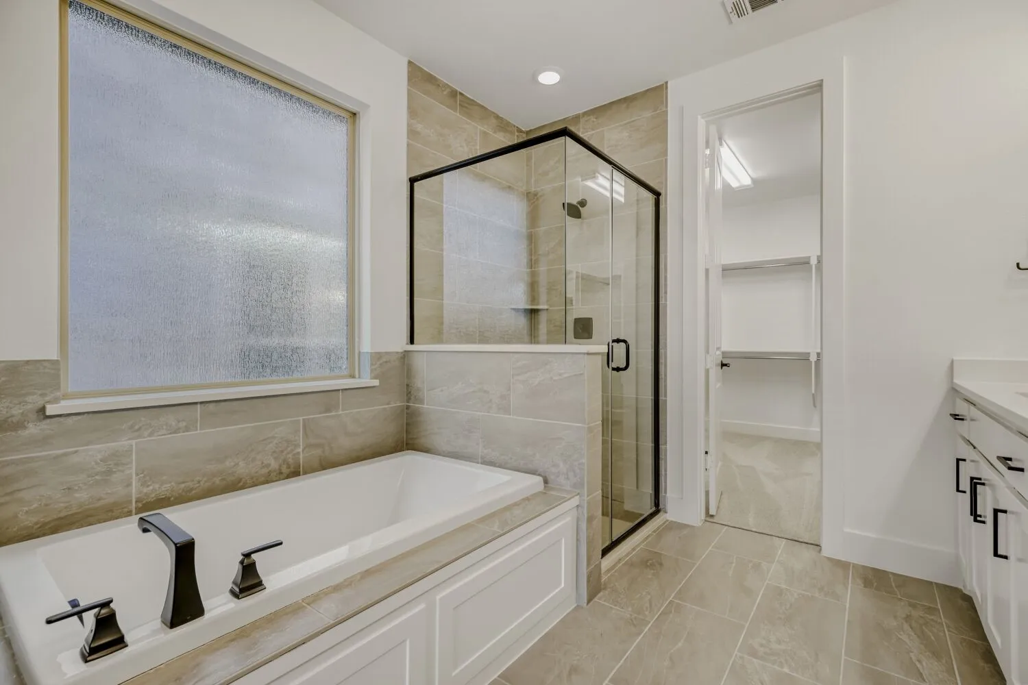 Bathroom featuring vanity, a bath, a walk in closet, and a shower stall