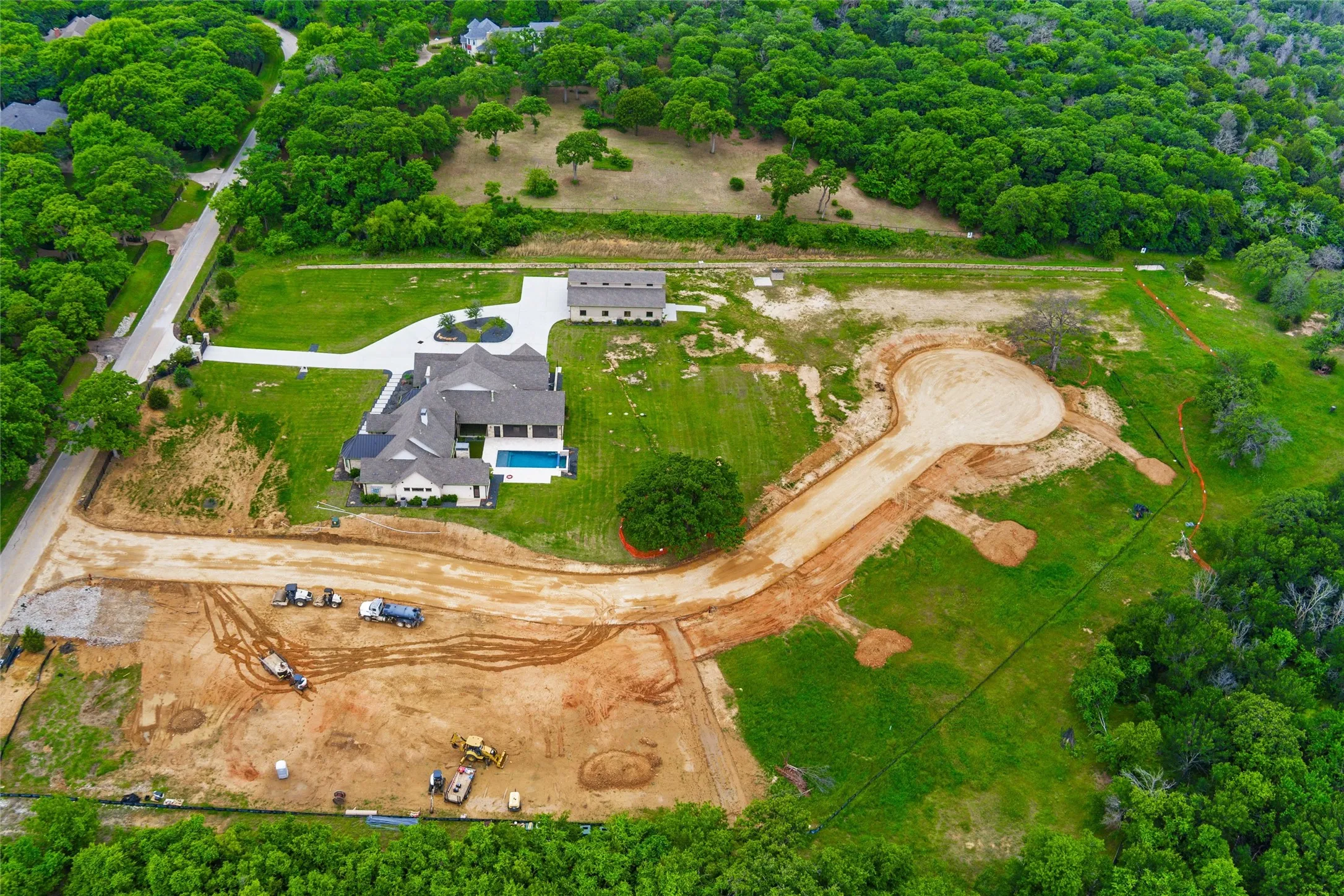 Expansive property featuring a contemporary residence, a detached auxiliary building, a rectangular swimming pool, and a large cul-de-sac development site