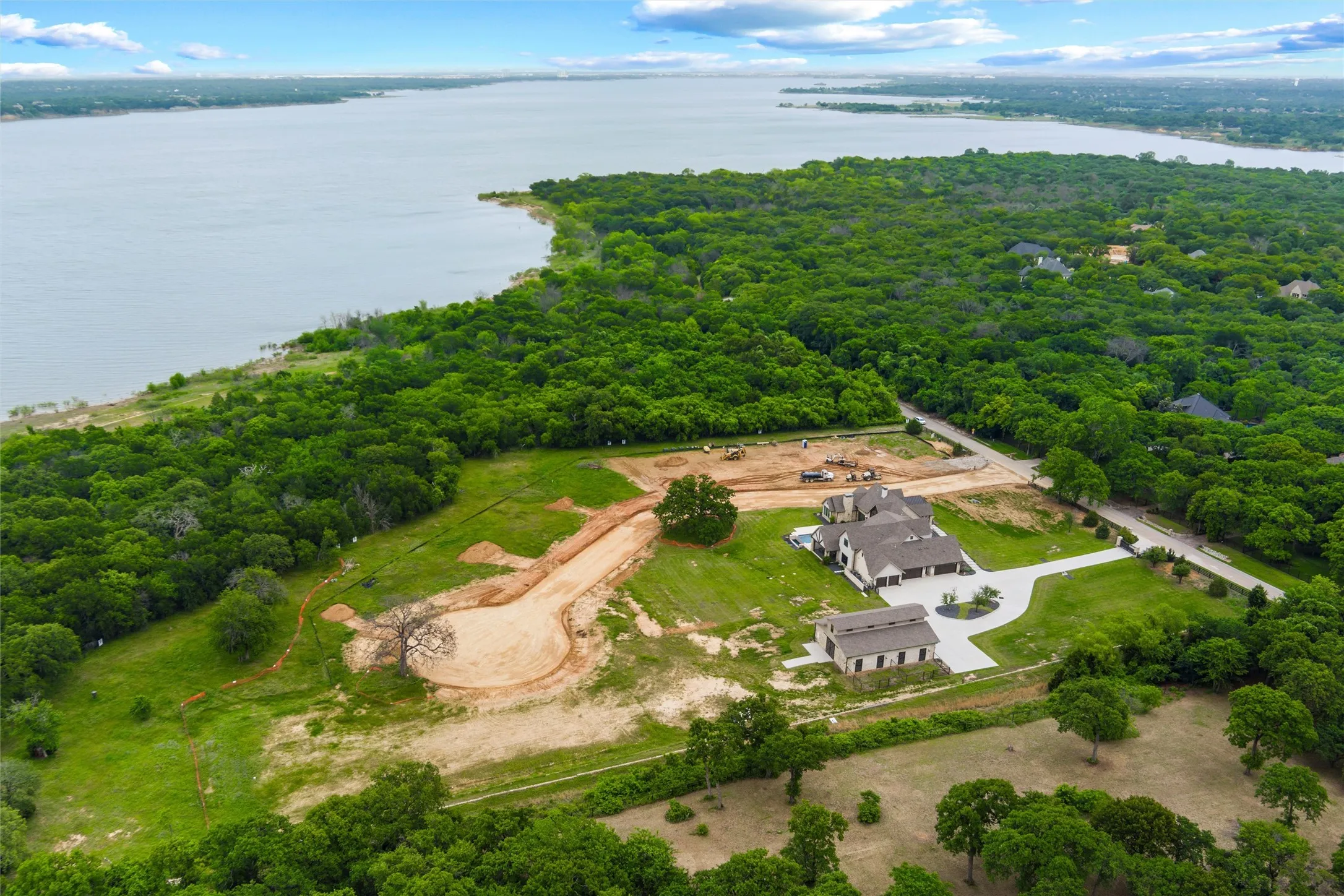 Expansive estate featuring a large main residence, a separate auxiliary building, a winding paved driveway, and mature landscaping