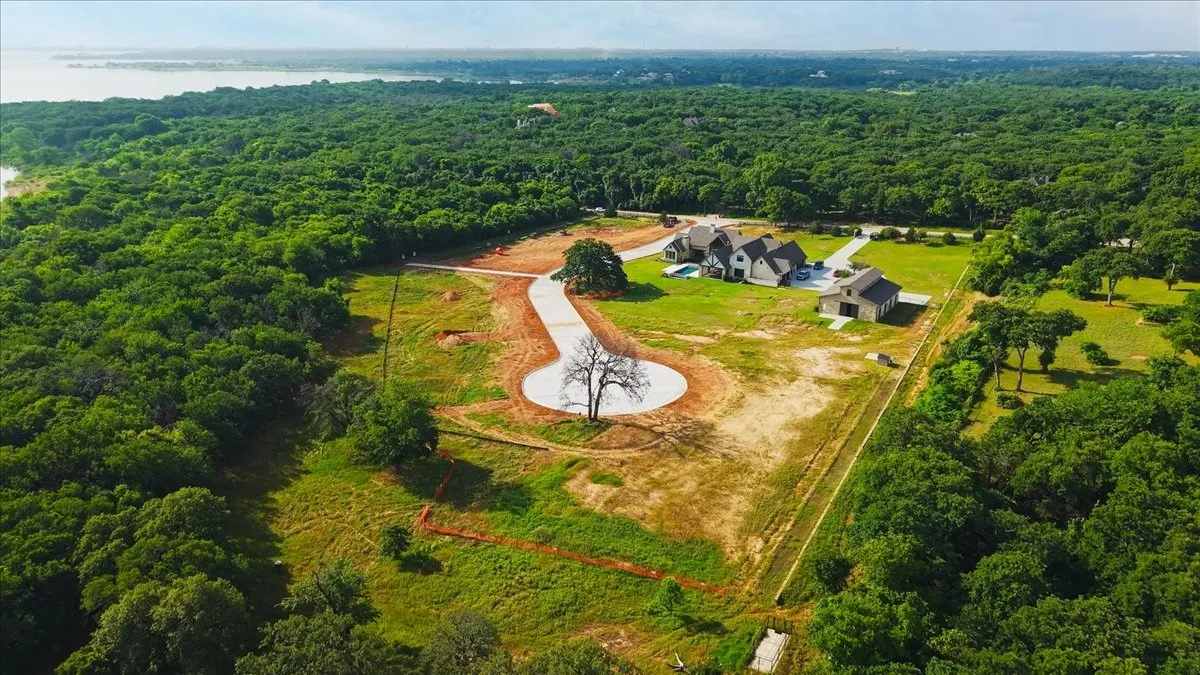 Expansive land parcel featuring a cul-de-sac drive and mature tree, bordered by dense woodlands