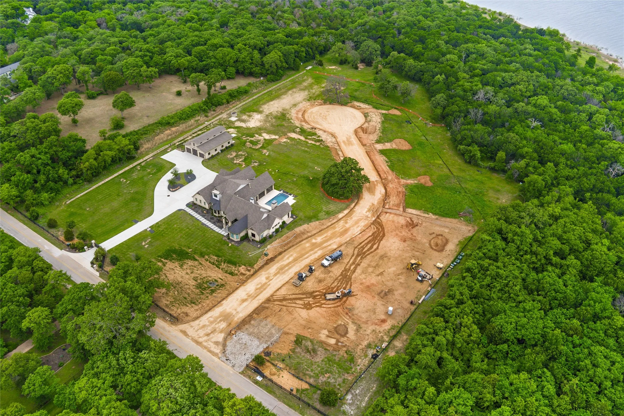 Expansive property featuring a large residence, detached auxiliary building, swimming pool, and extensive wooded areas