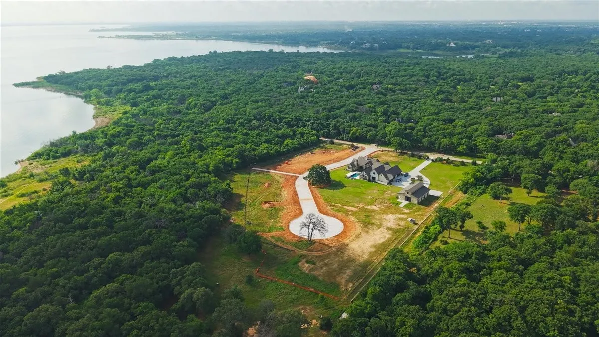 Expansive waterfront property featuring a cleared building site, mature tree cover, and direct water access