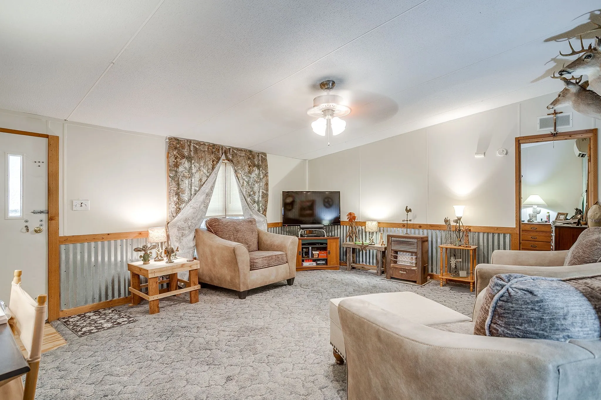 Carpeted living area with a wainscoted wall, lofted ceiling, and a ceiling fan