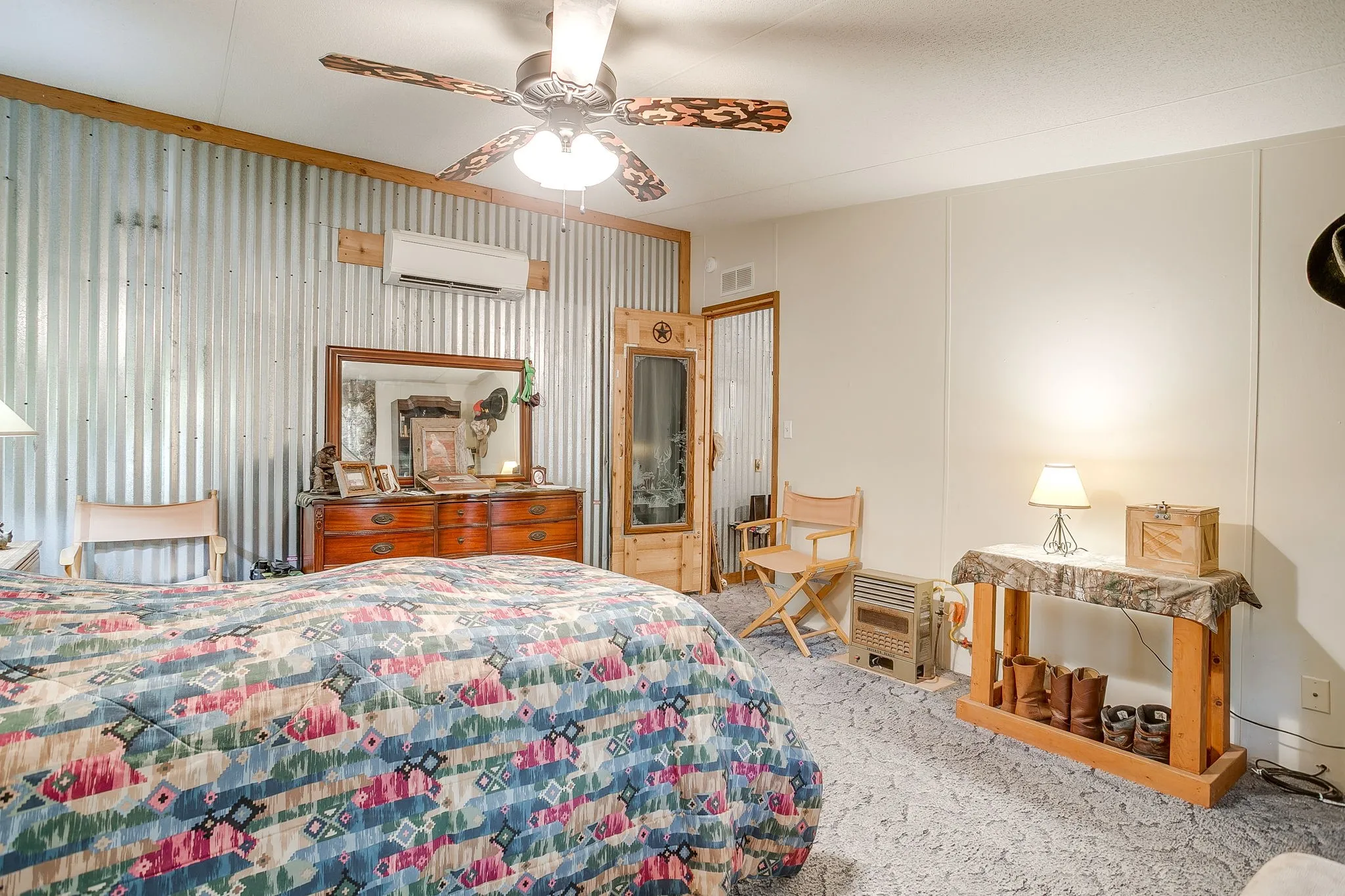 Carpeted bedroom featuring ceiling fan, a decorative wall, and a wall mounted AC
