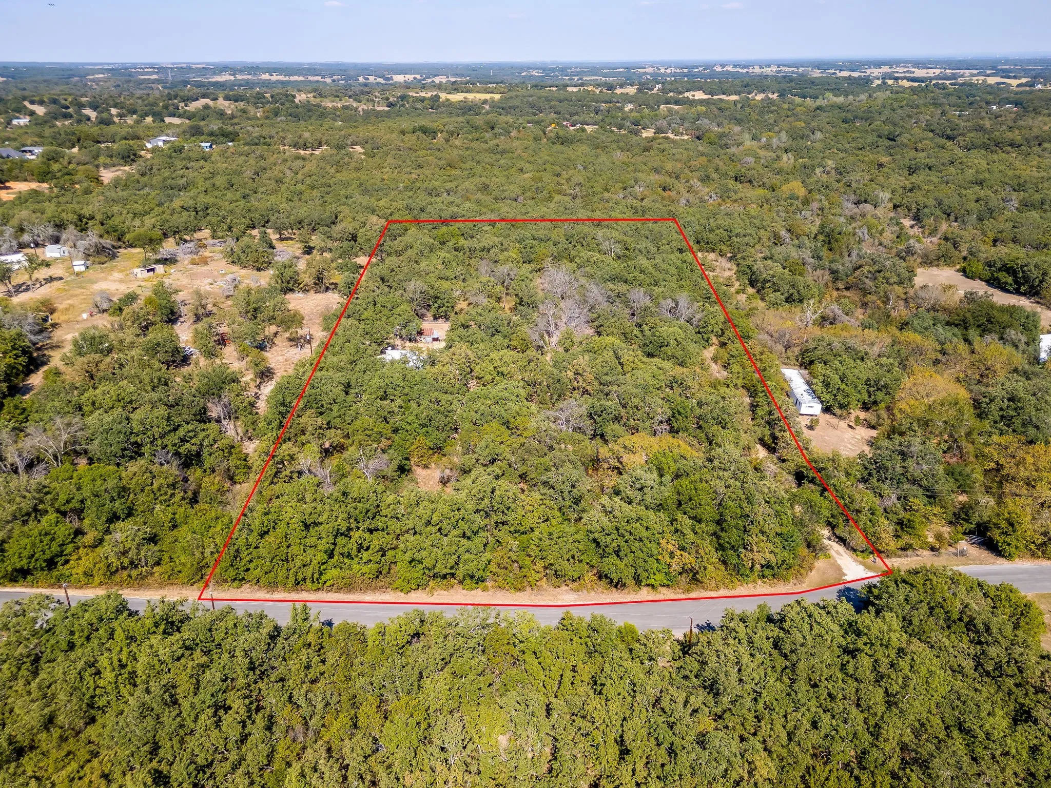 Aerial overview of property's location with property parcel outlined and a forest