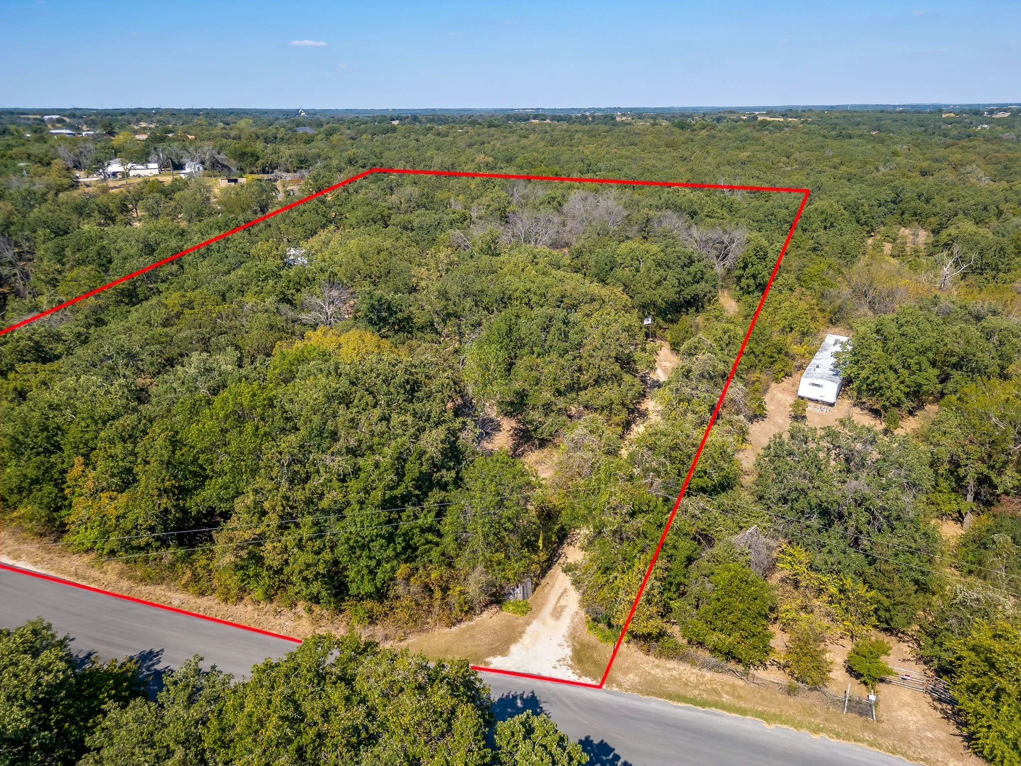 Aerial view of property's location featuring property parcel outlined and a forest