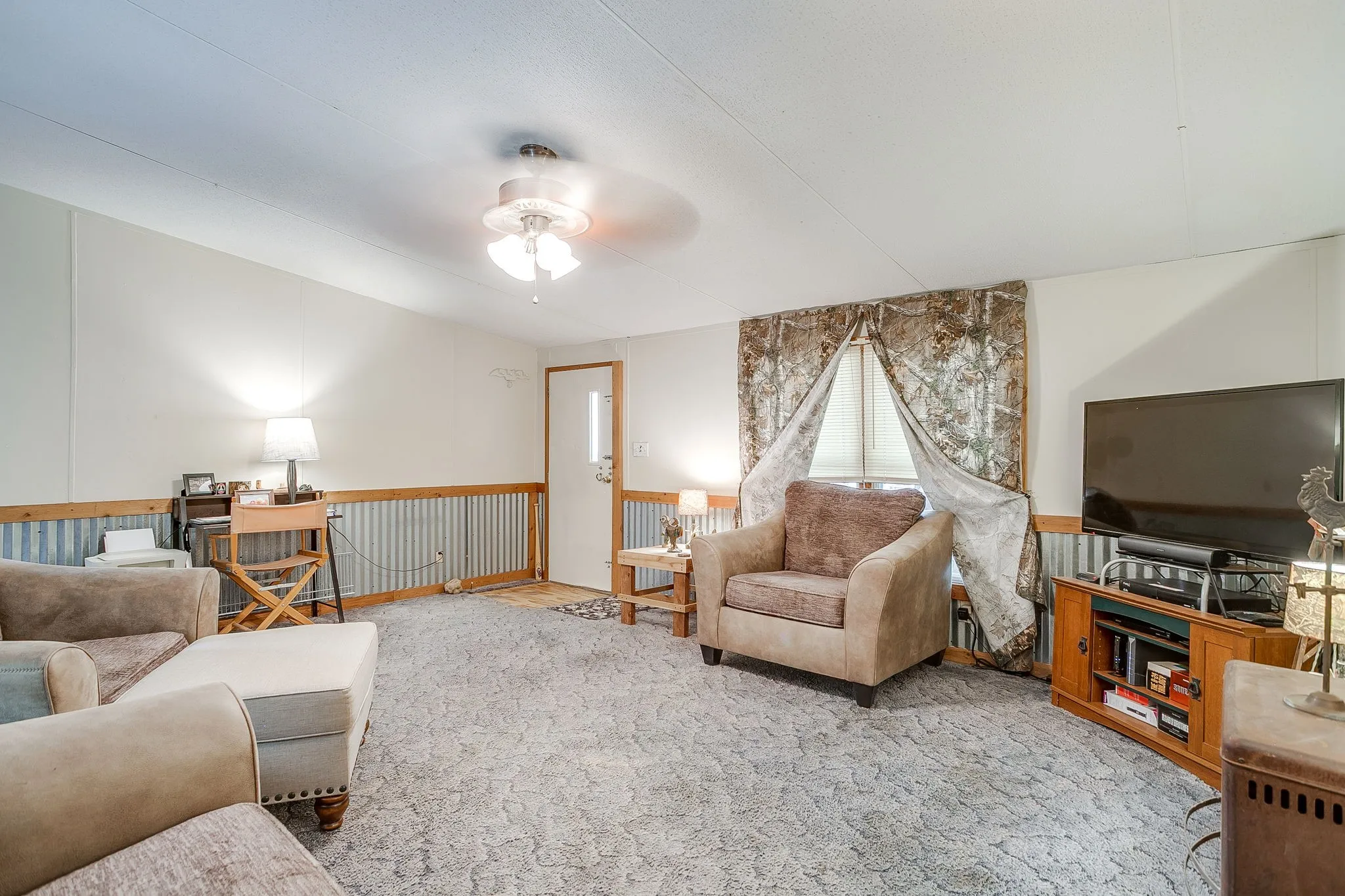 Living area featuring wainscoting, carpet floors, and ceiling fan