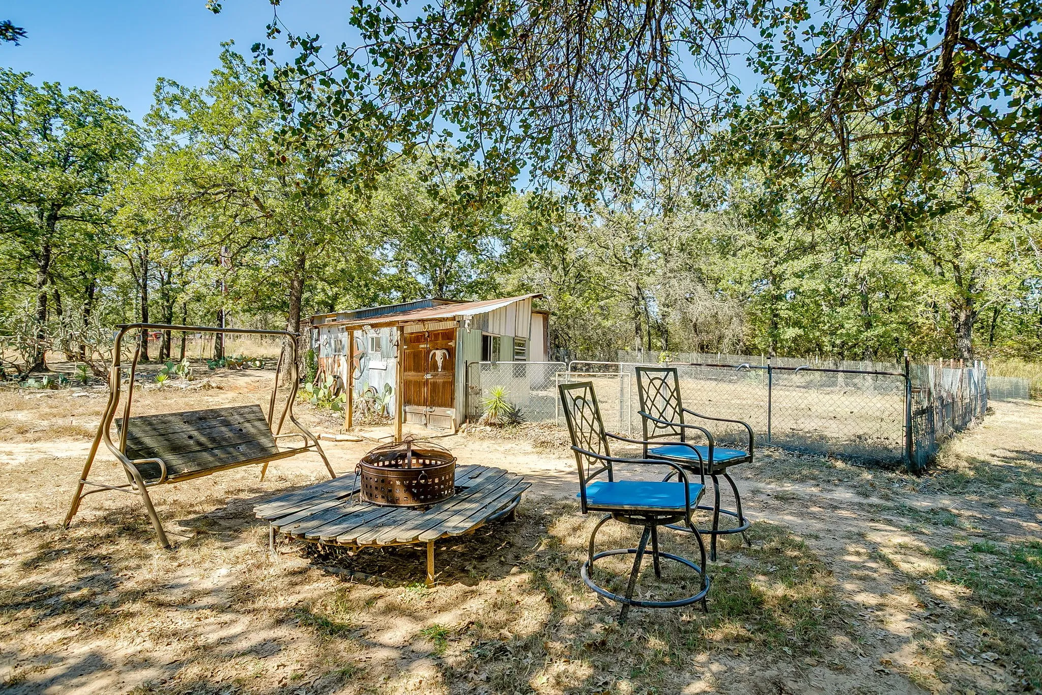 View of yard with a fire pit, an outdoor structure, and view of wooded area