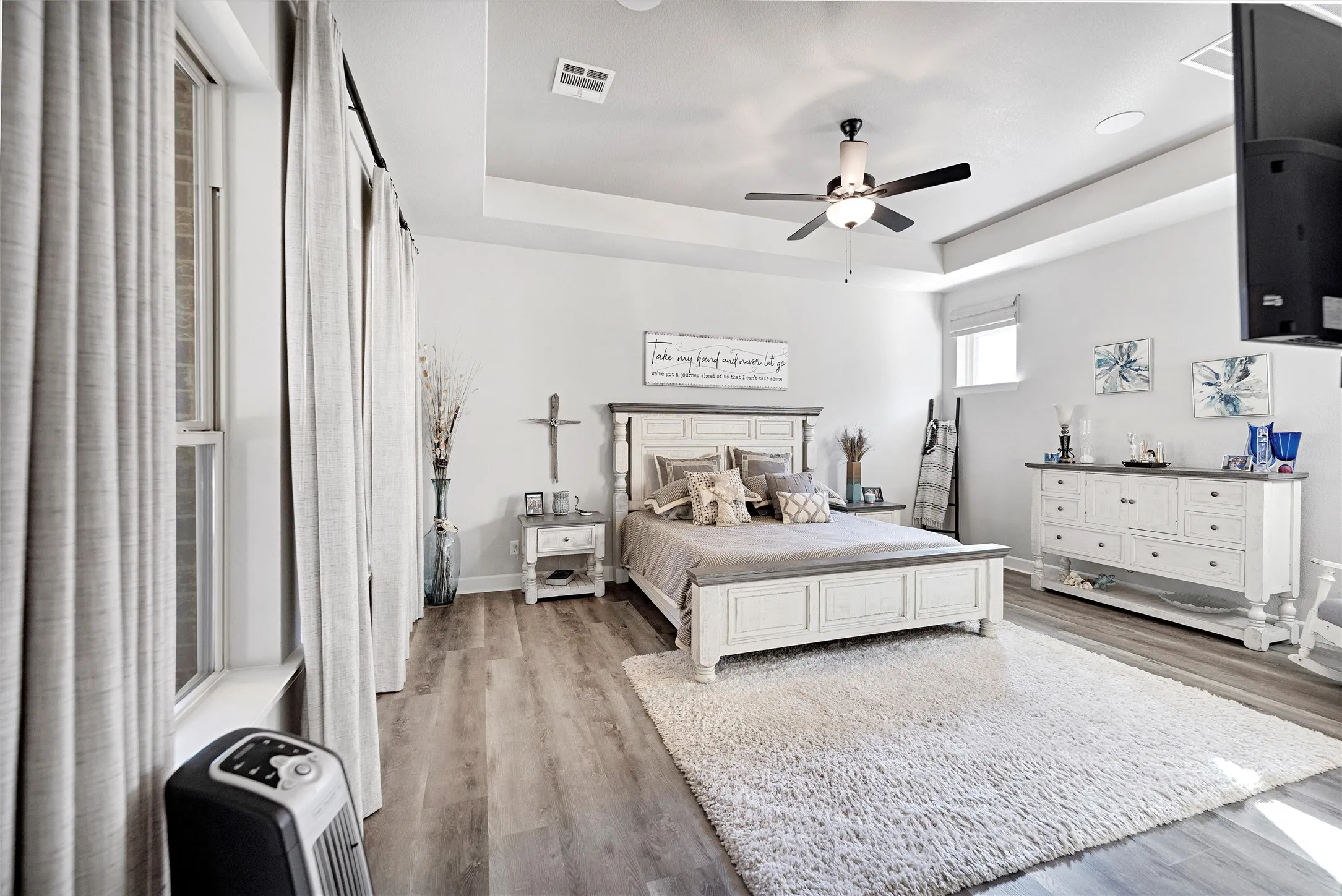 Bedroom with a tray ceiling, light wood-style flooring, and ceiling fan