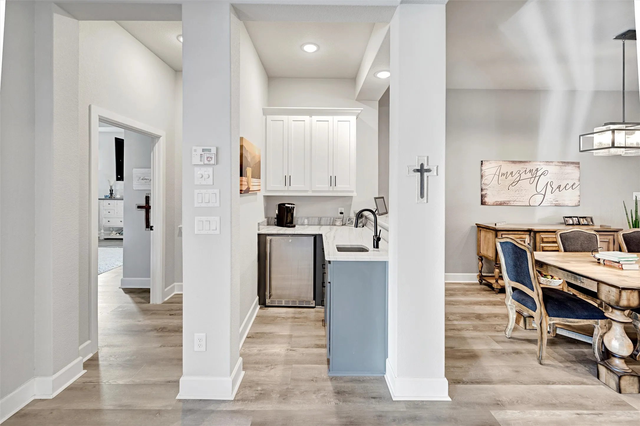 Bar with white cabinetry, light wood-style floors, wine cooler, light stone counters, and a chandelier