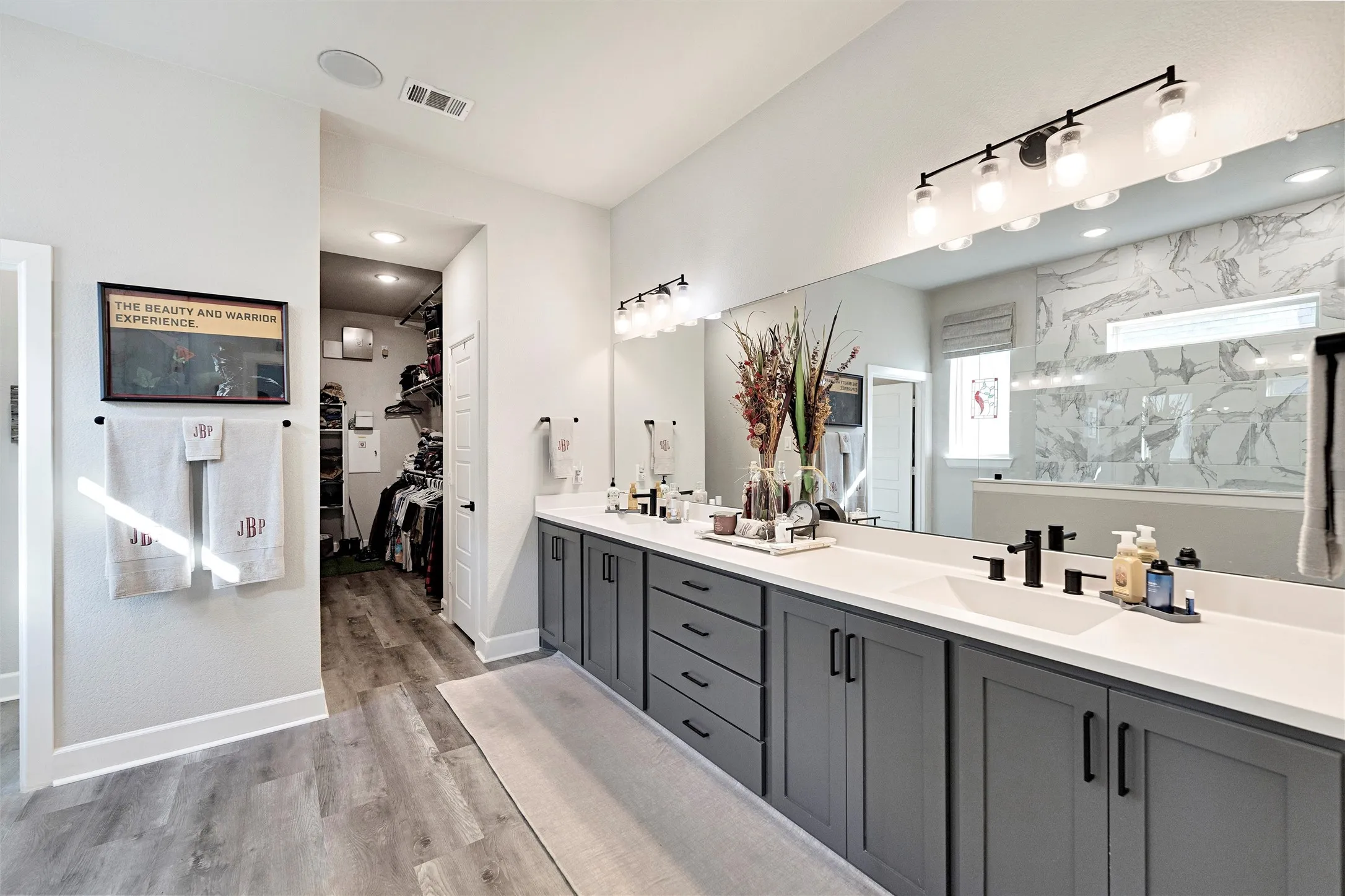 Full bath featuring double vanity, light wood finished floors, a spacious closet, a marble finish shower, and recessed lighting