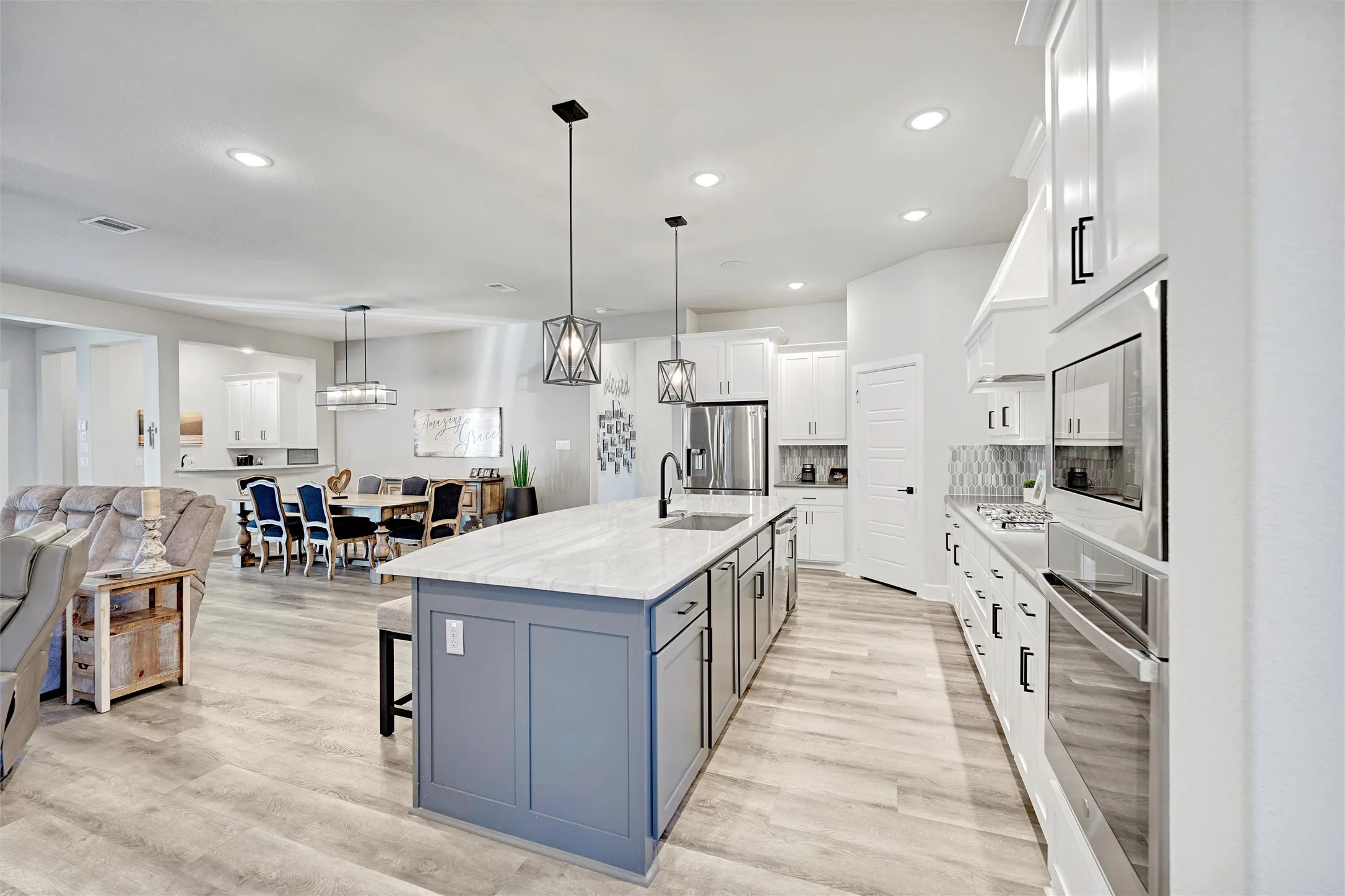 Kitchen with a kitchen breakfast bar, open floor plan, white cabinets, decorative backsplash, and light stone countertops