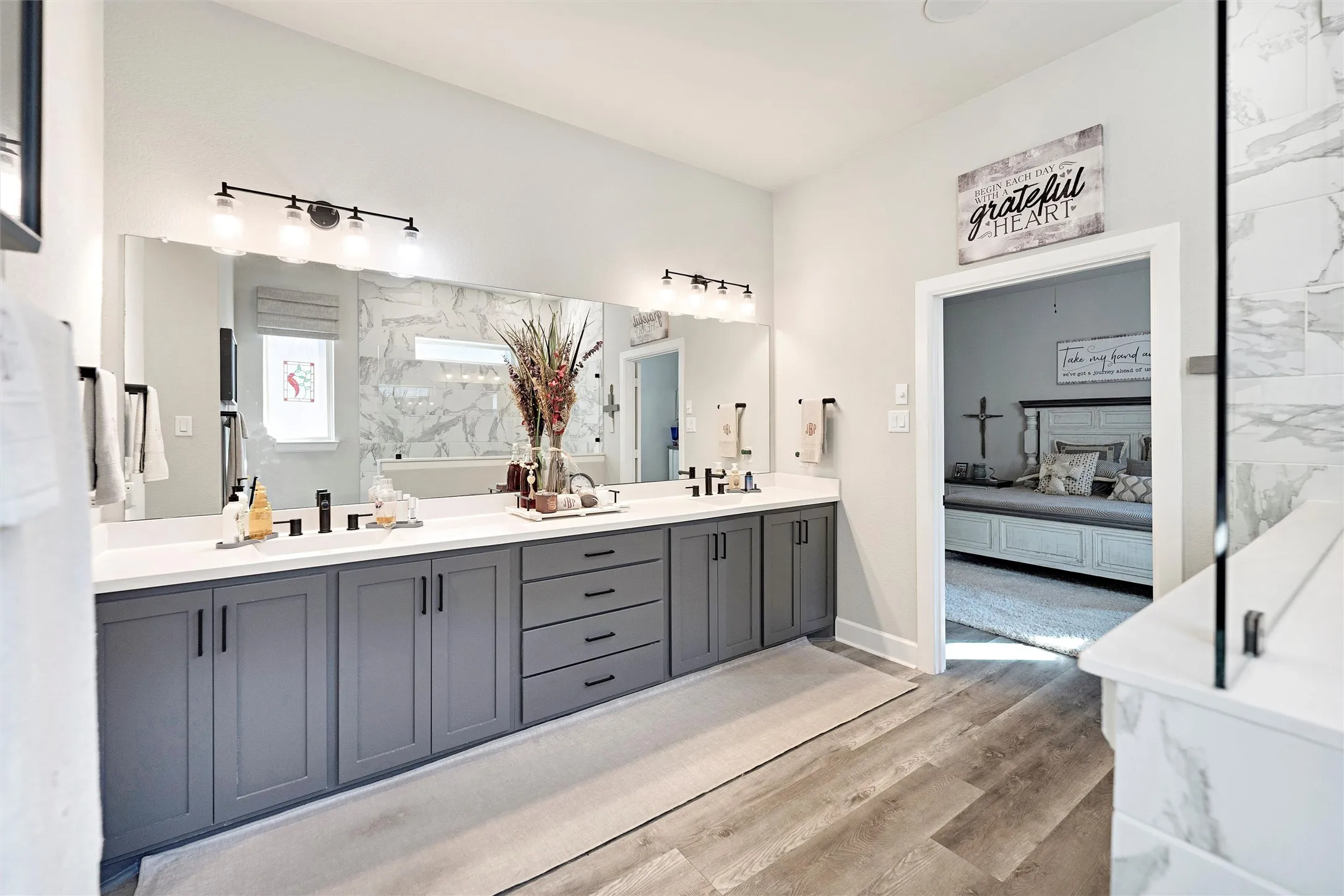 Full bathroom with double vanity, light wood-type flooring, and ensuite bathroom