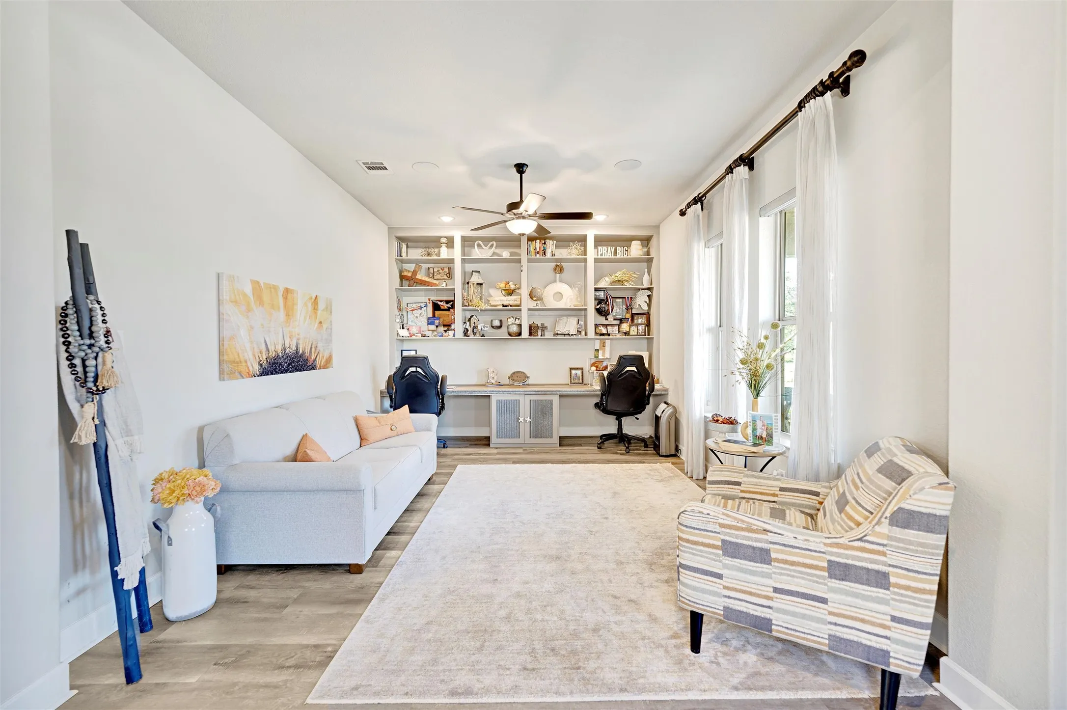 Sitting room featuring built in desk, light wood finished floors, and ceiling fan