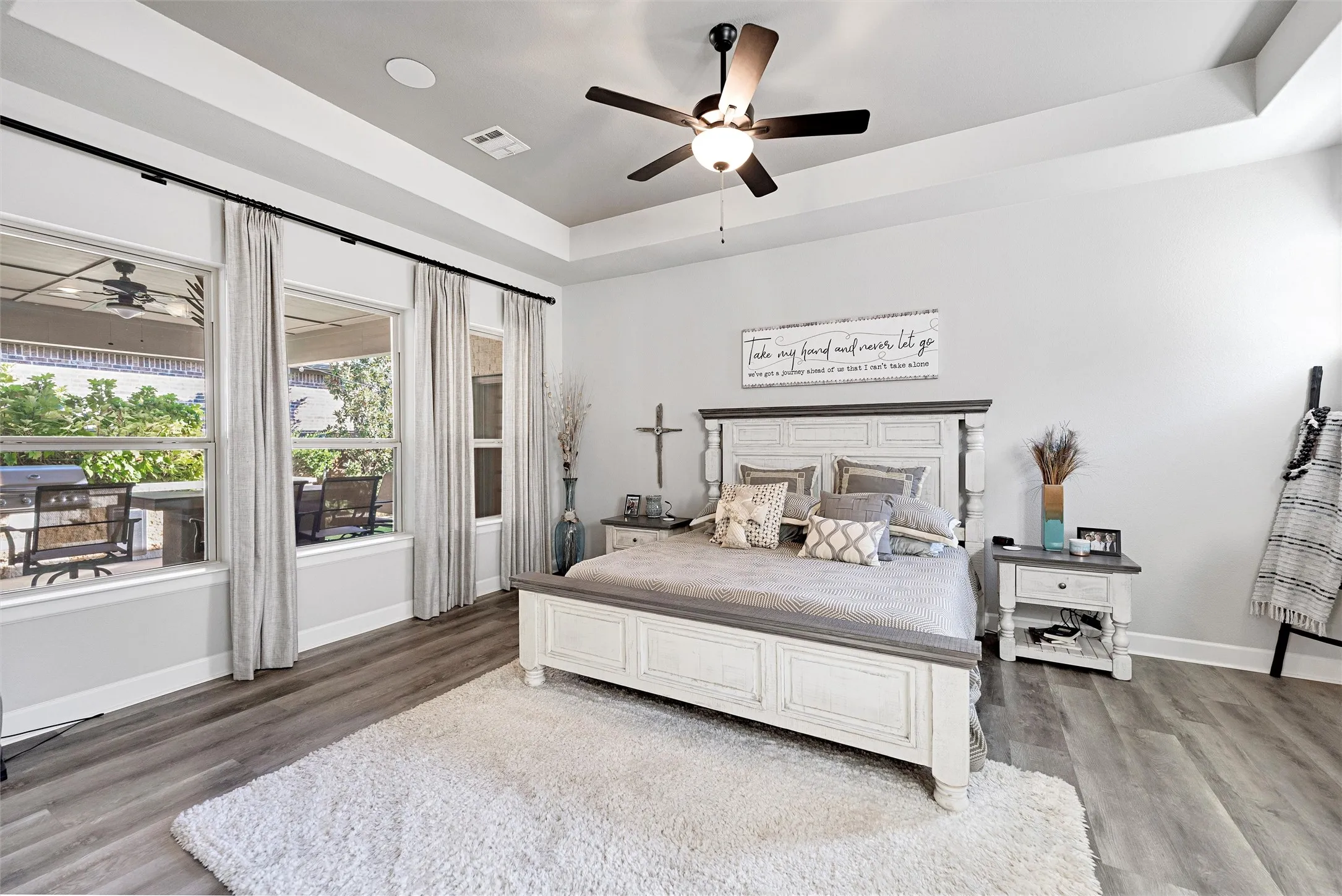 Bedroom with a raised ceiling, wood finished floors, and ceiling fan