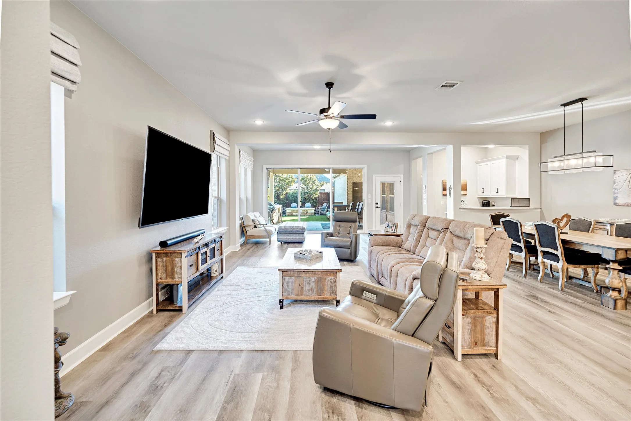 Living area with light wood-style flooring, ceiling fan, and recessed lighting