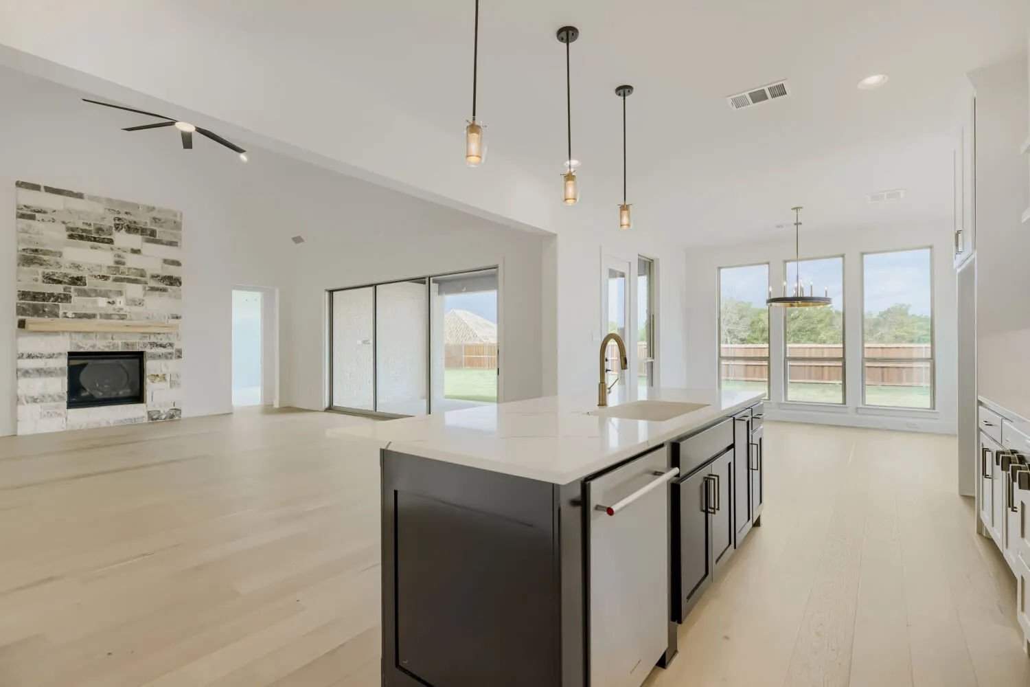 Dual tone kitchen with a tile fireplace, light wood-style flooring, open floor plan, a center island with sink, and dishwasher