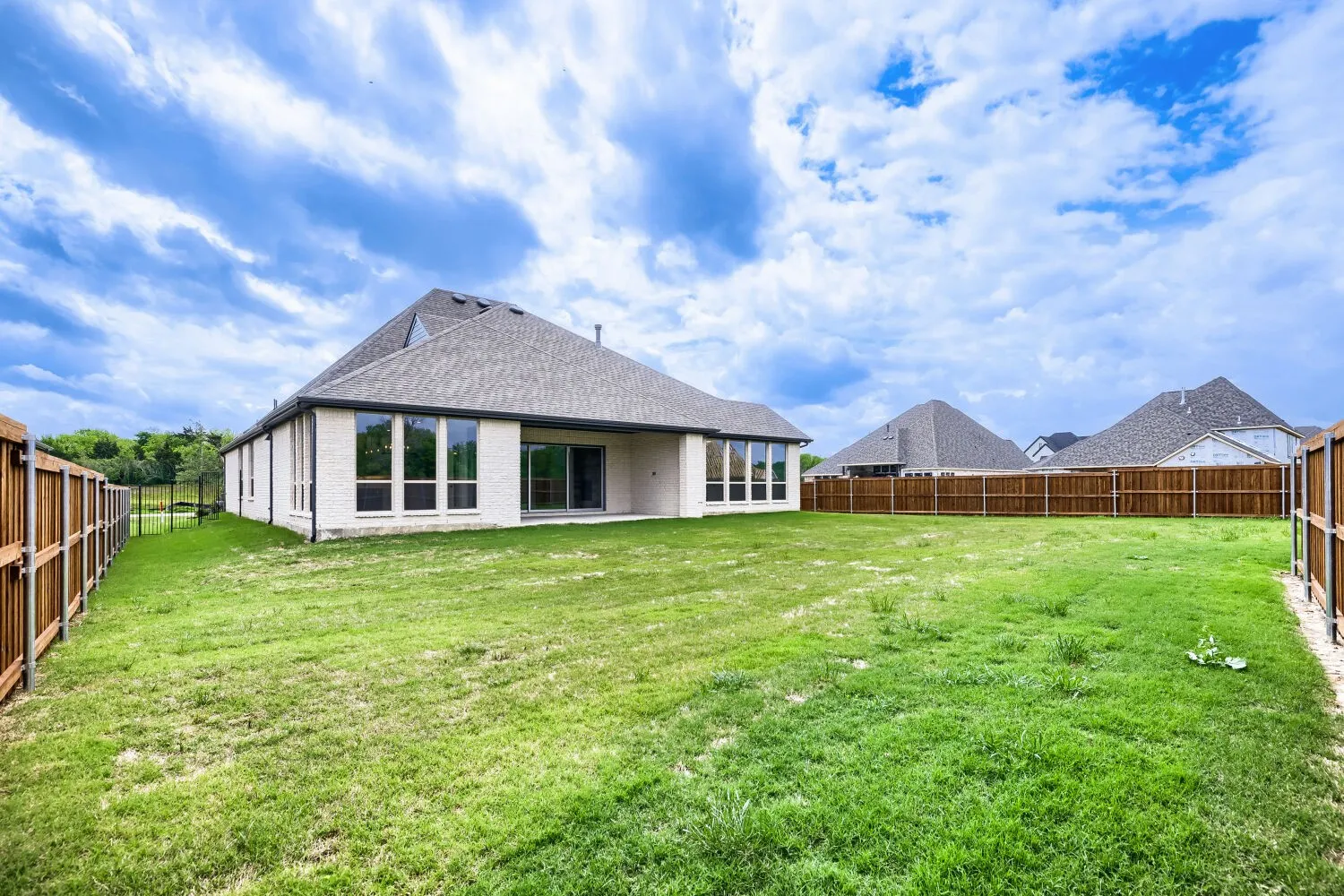 Rear view of house featuring a patio, a fenced backyard, brick siding, and a shingled roof