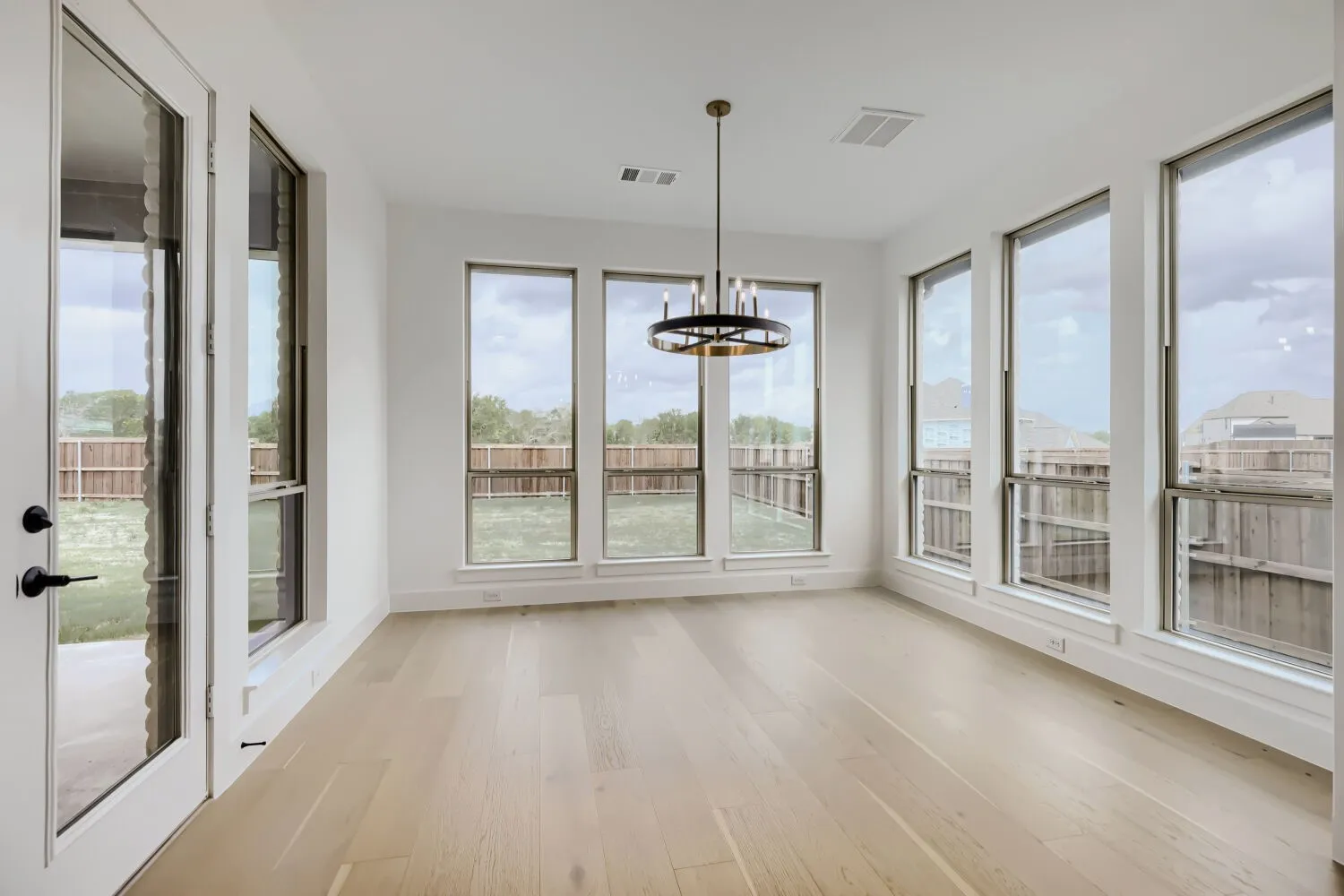 Unfurnished sunroom featuring wood finished floors, healthy amount of natural light, and a chandelier