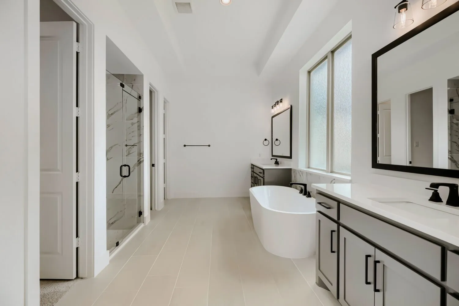 Bathroom with two vanities, a marble finish shower, and a freestanding tub