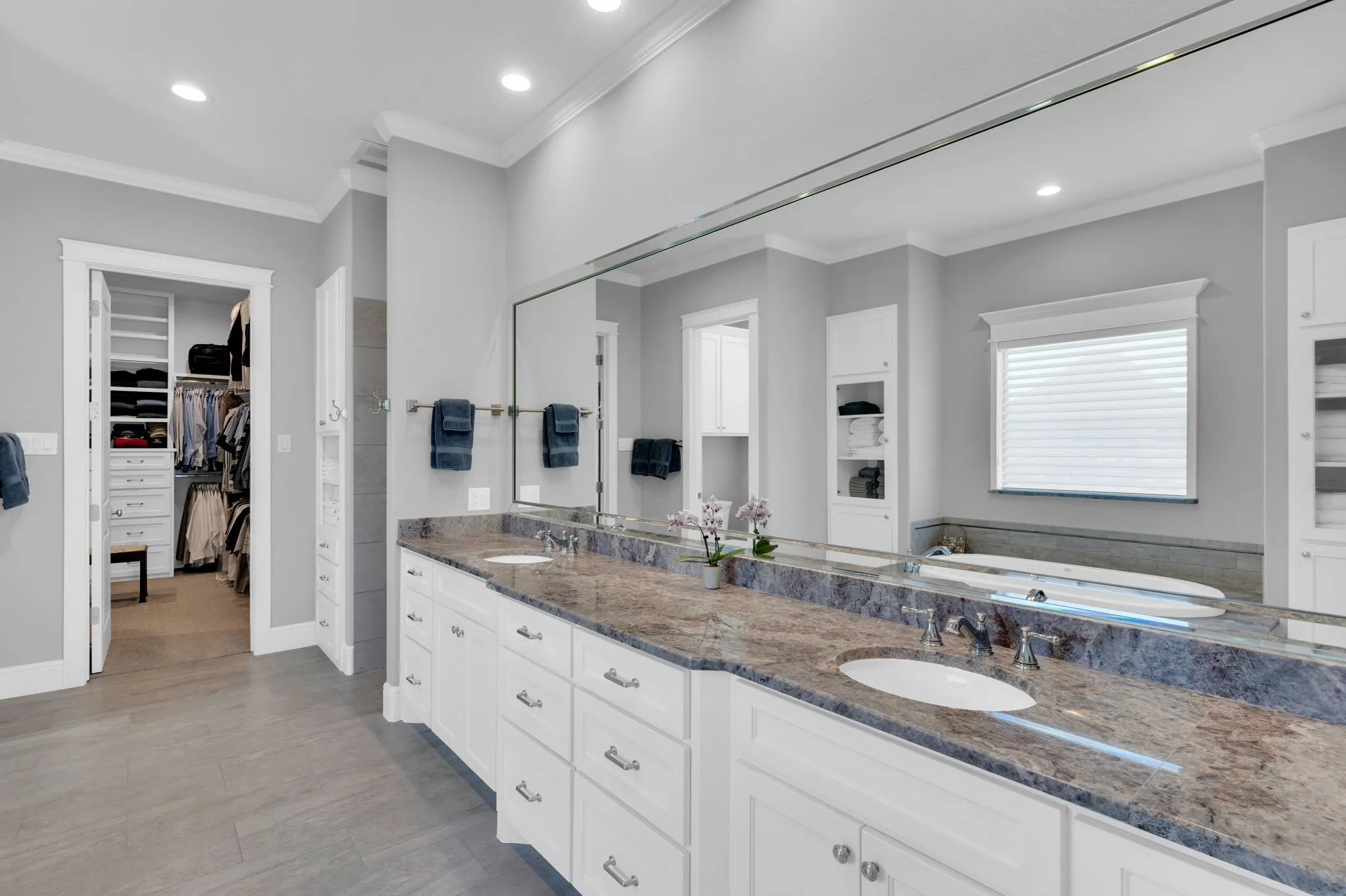 Bathroom featuring a walk in closet, double vanity, ornamental molding, recessed lighting, and light wood-type flooring