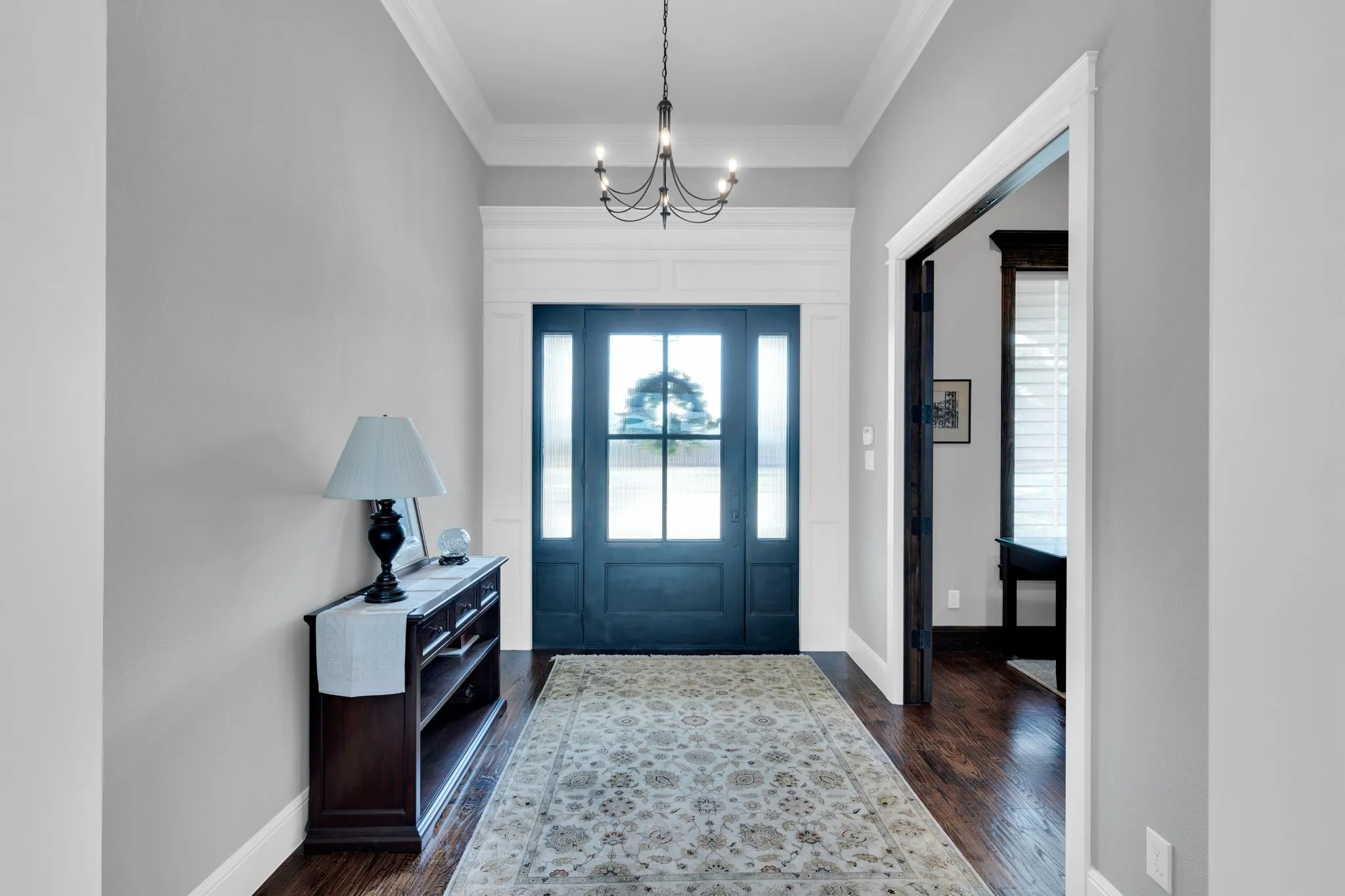 Entrance foyer featuring ornamental molding, a chandelier, and dark wood-type flooring