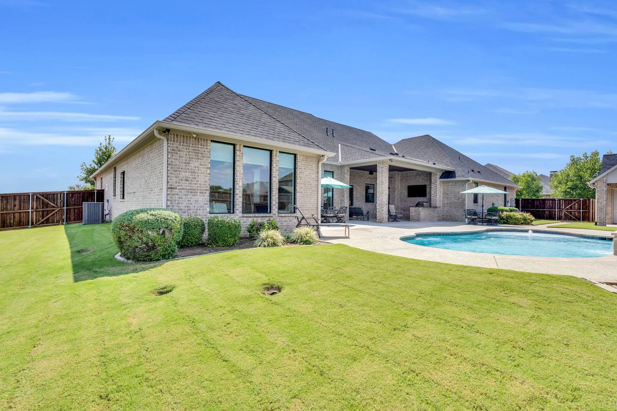 Rear view of house with a fenced backyard, a patio area, brick siding, and roof with shingles