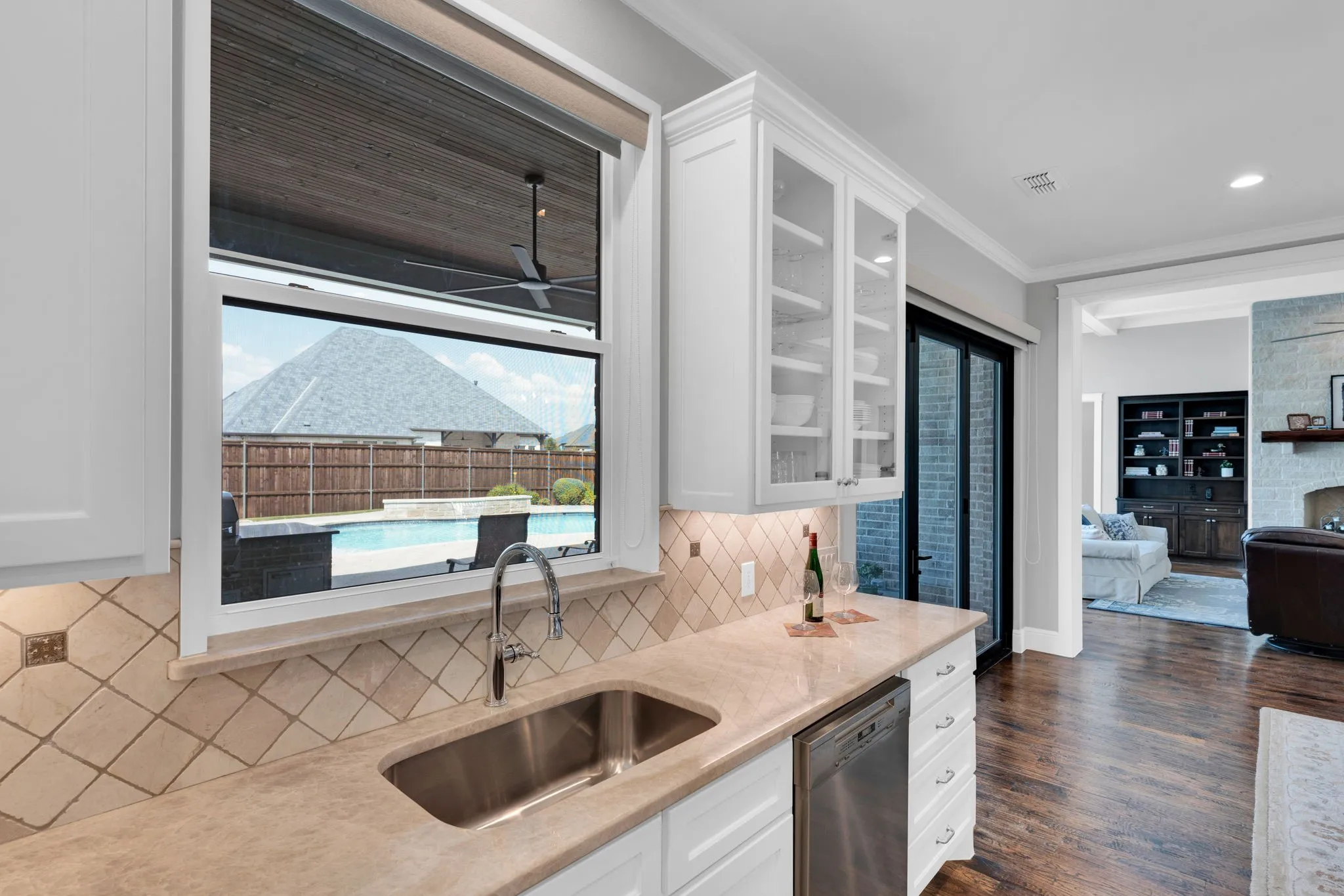 Kitchen featuring white cabinets, ornamental molding, light stone counters, dark wood finished floors, and stainless steel dishwasher