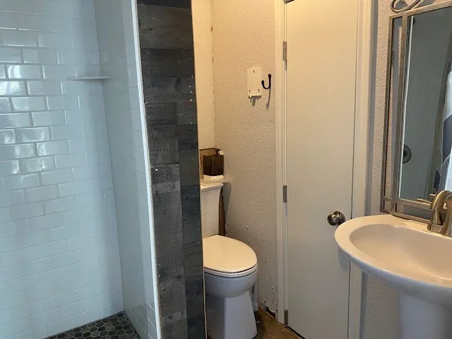 Full bathroom with a textured wall and a stall shower