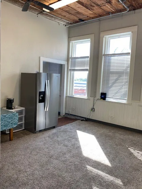 Kitchen with fridge and light colored carpet