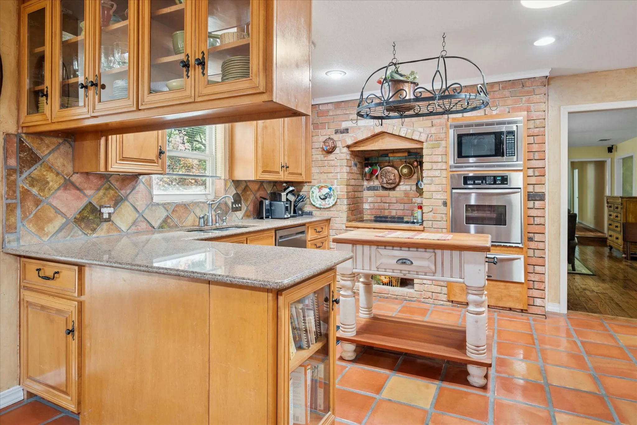 Kitchen with glass insert cabinets, light stone countertops, appliances with stainless steel finishes, tasteful backsplash, and a warming drawer