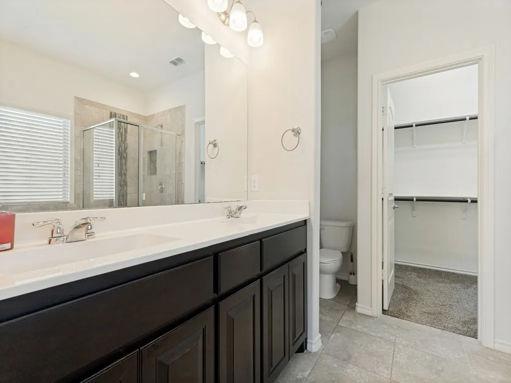 Double vanity with undermount sinks and dark cabinetry, large mirror, and chrome fixtures
