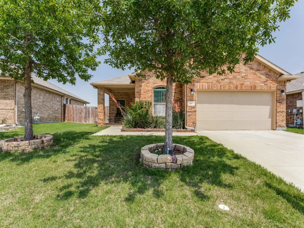 Brick facade residence featuring an attached garage, covered entryway, concrete driveway, and a fenced side yard