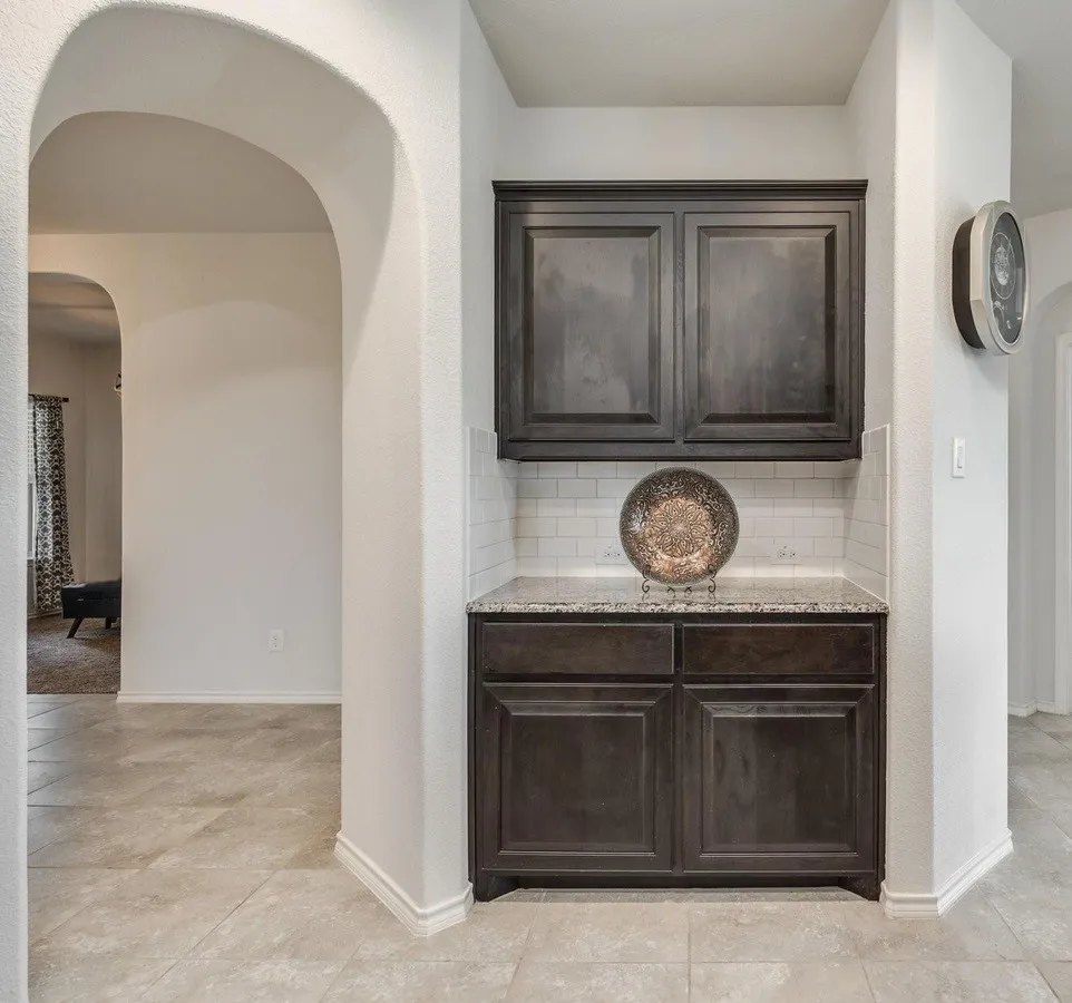 Built-in cabinetry with dark wood-finish doors, a light-toned granite-style countertop, and subway tile backsplash