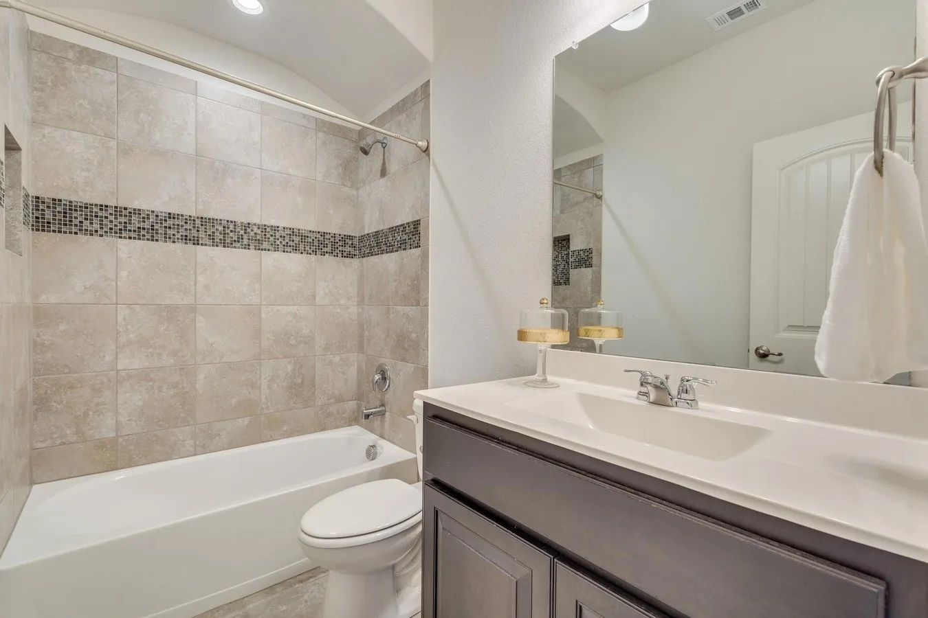 Bathroom featuring a tub/shower combination with tile surround and a mosaic accent band