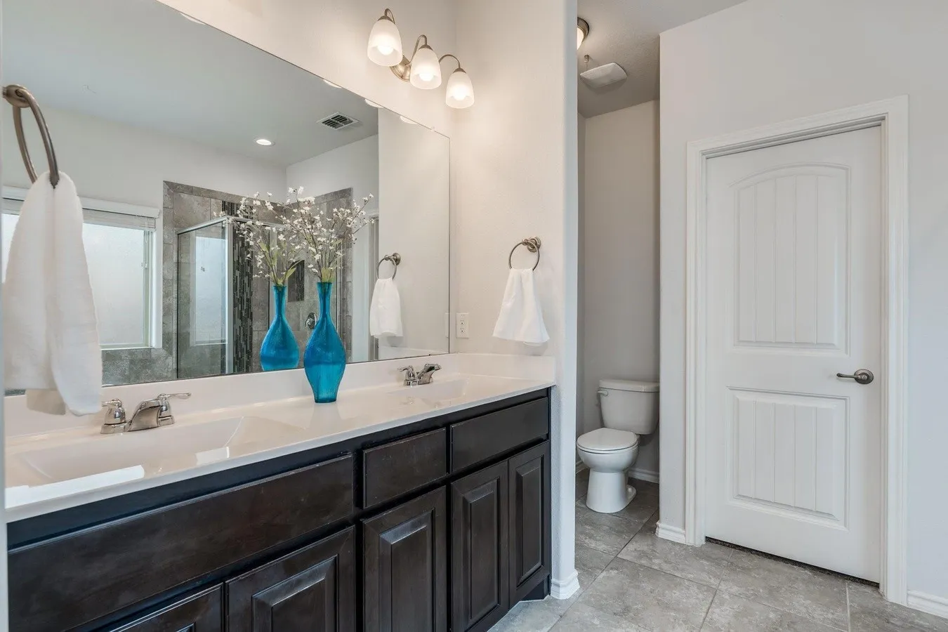 Double vanity with dark wood cabinetry and white countertops