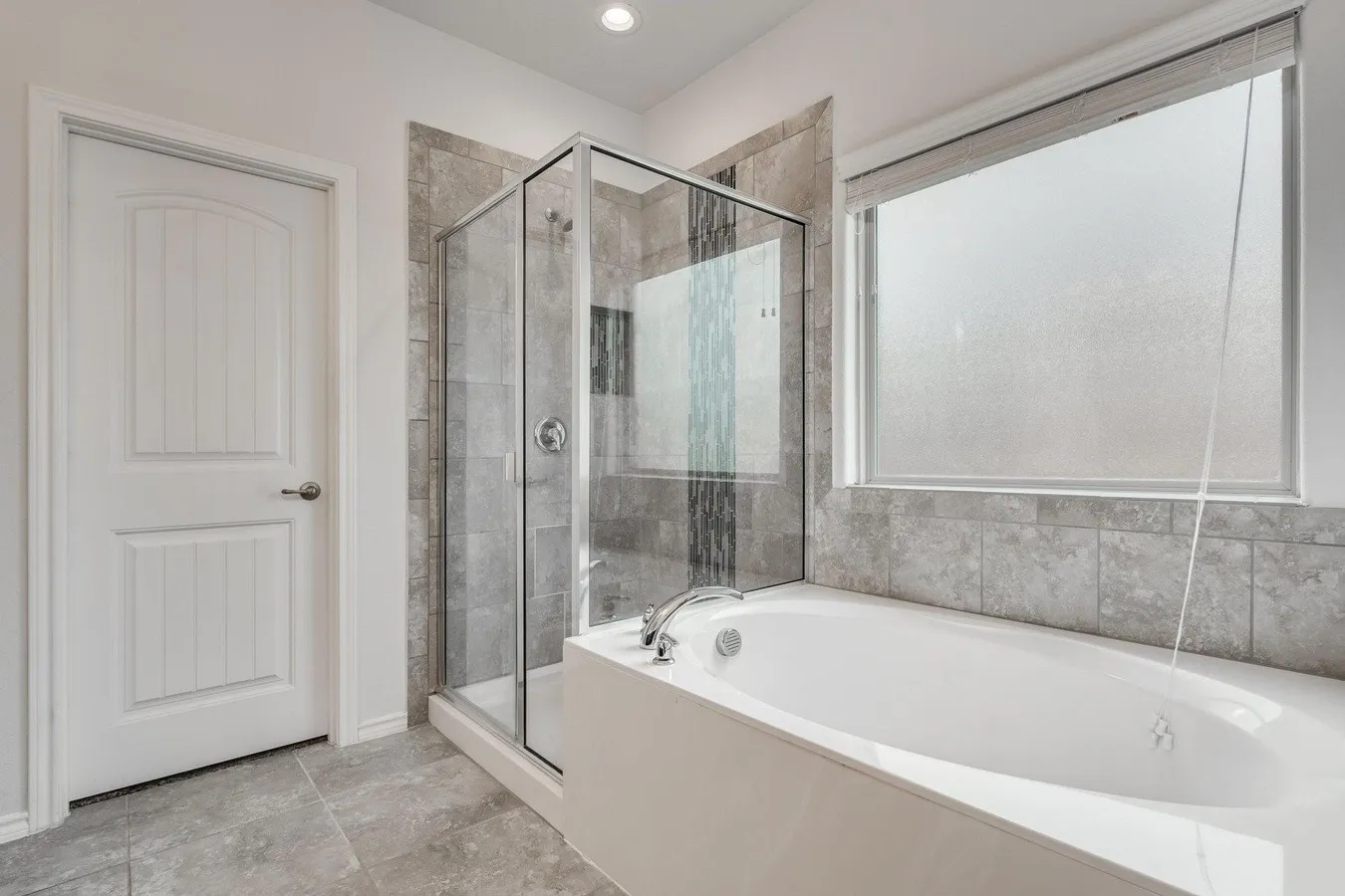 Bathroom featuring a built-in soaking tub with deck-mounted faucet, a separate glass-enclosed shower with tiled walls, and a frosted window for privacy